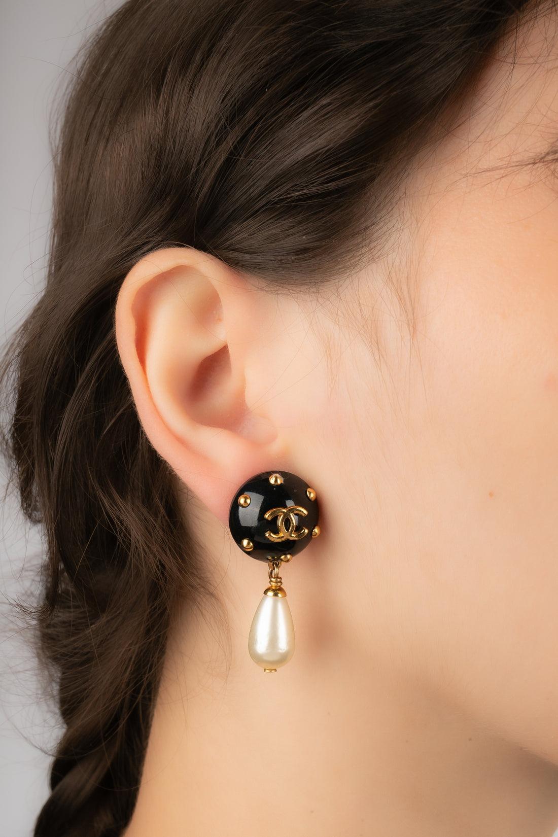CHANEL - (Made in France) Golden metal clip-on earrings with black bakelite and costume pearly drops. 1996 Cruise Collection under the artistic direction of Karl Lagerfeld.

Additional information:
Condition: Very good condition
Dimensions: