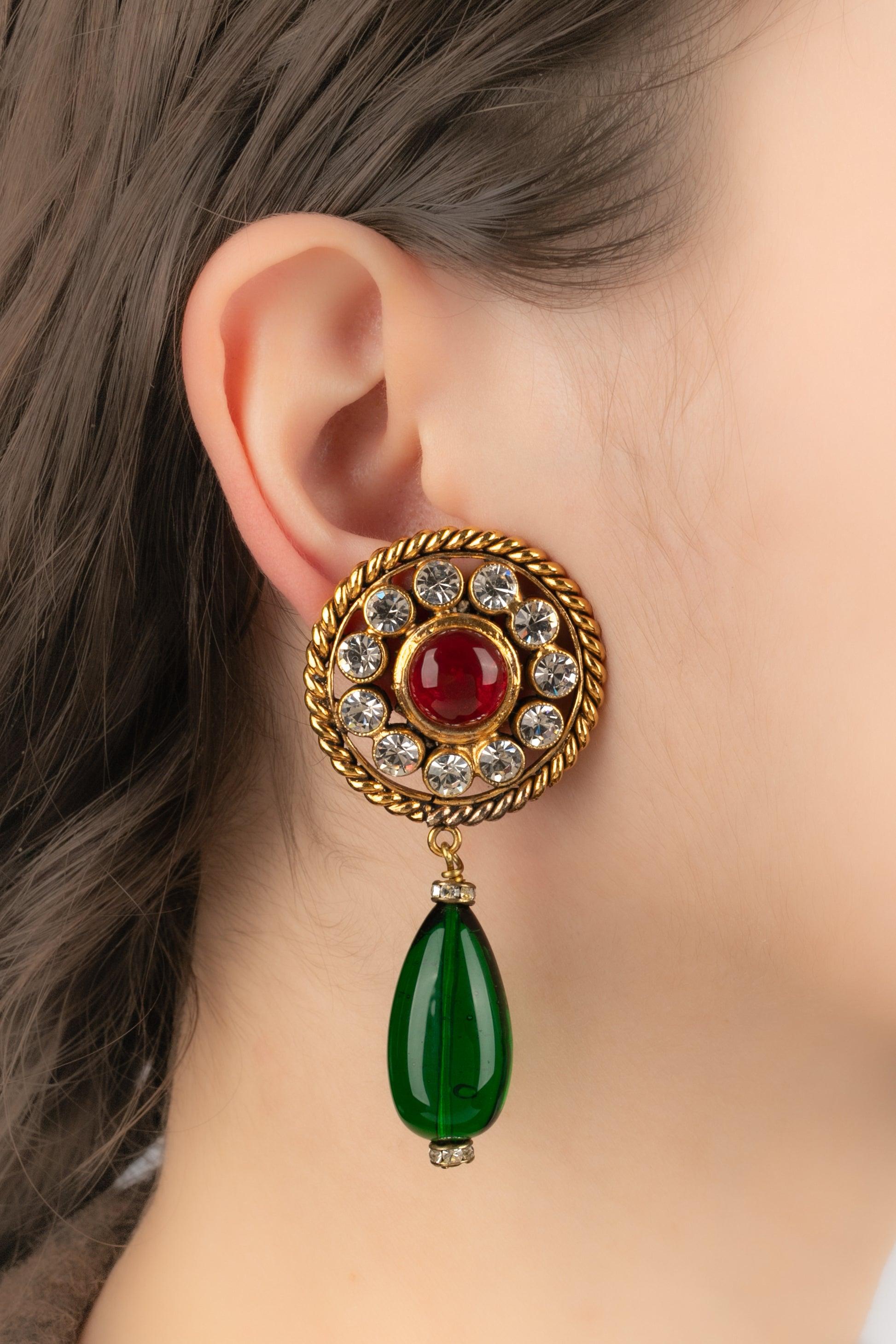 CHANEL - (Made in France) Golden metal openwork clip-on earrings decorated with rhinestones, a red glass paste cabochon in the center, and a green glass paste drop. 2cc3 Collection. Jewelry engraved with the S of Sales.

Additional