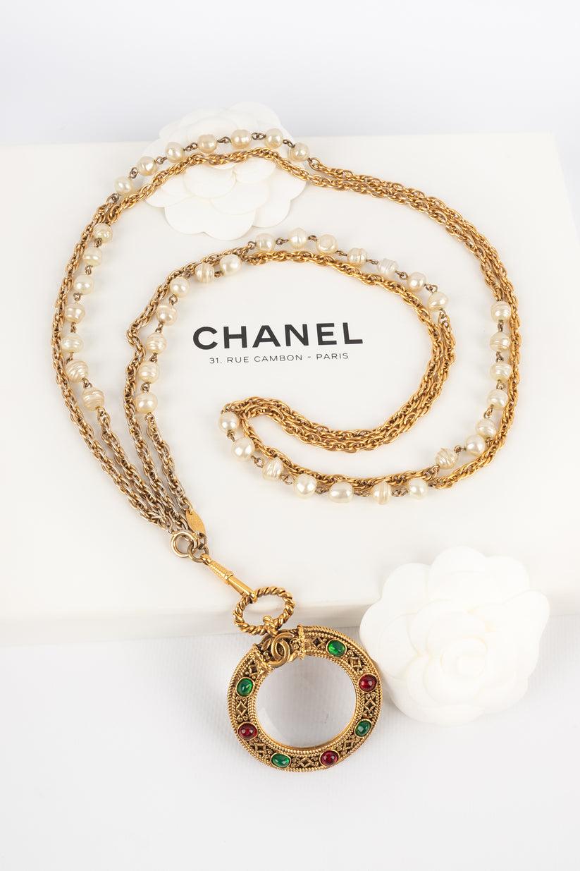 Chanel - (Made in France) Collier loupe en métal doré avec des perles fantaisie et un pendentif orné de minuscules cabochons en pâte de verre. Collectional 1985.

Informations complémentaires :
Condit : Bon état
Dimensions : Longueur : 100