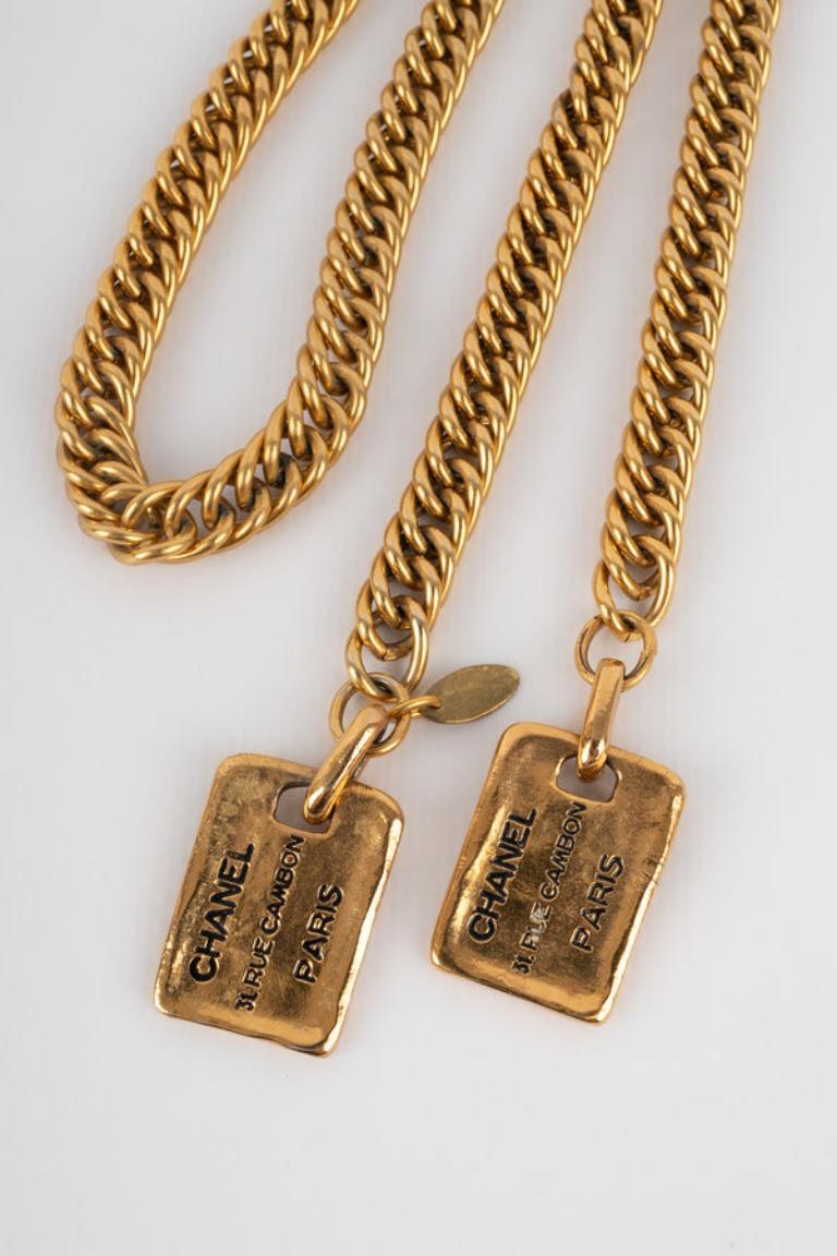 Chanel - (Made in France) Goldene Metallkette im Krawattenstil mit zwei Plaketten am Ende. Schmuck aus den 1980er Jahren.

Zusätzliche Informationen: 
Zustand: Sehr guter Zustand
Abmessungen: Länge: 92 cm
Zeitraum: 20. Jahrhundert

Sellers Referenz: