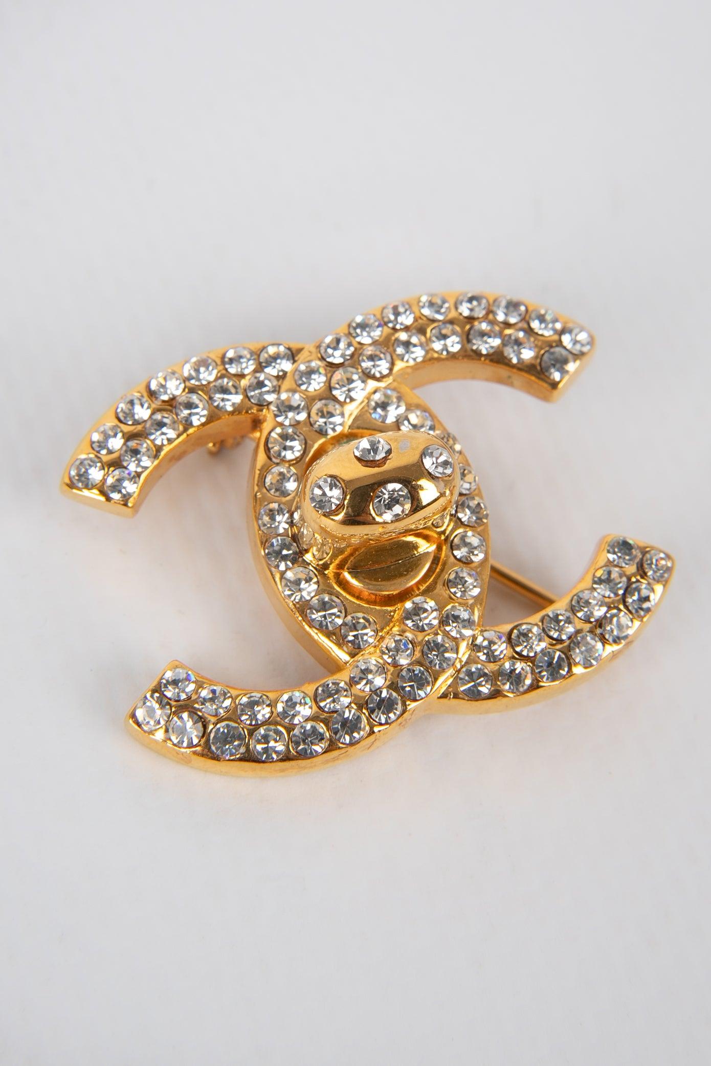 Chanel- (Made in France) Golden metal turnlock brooch ornamented with Swarovski rhinestones. 1996 Fall-Winter Collection.

Additional information:
Condition: Very good condition
Dimensions: Height: 2.5 cm
Period: 20th Century

Seller Reference: