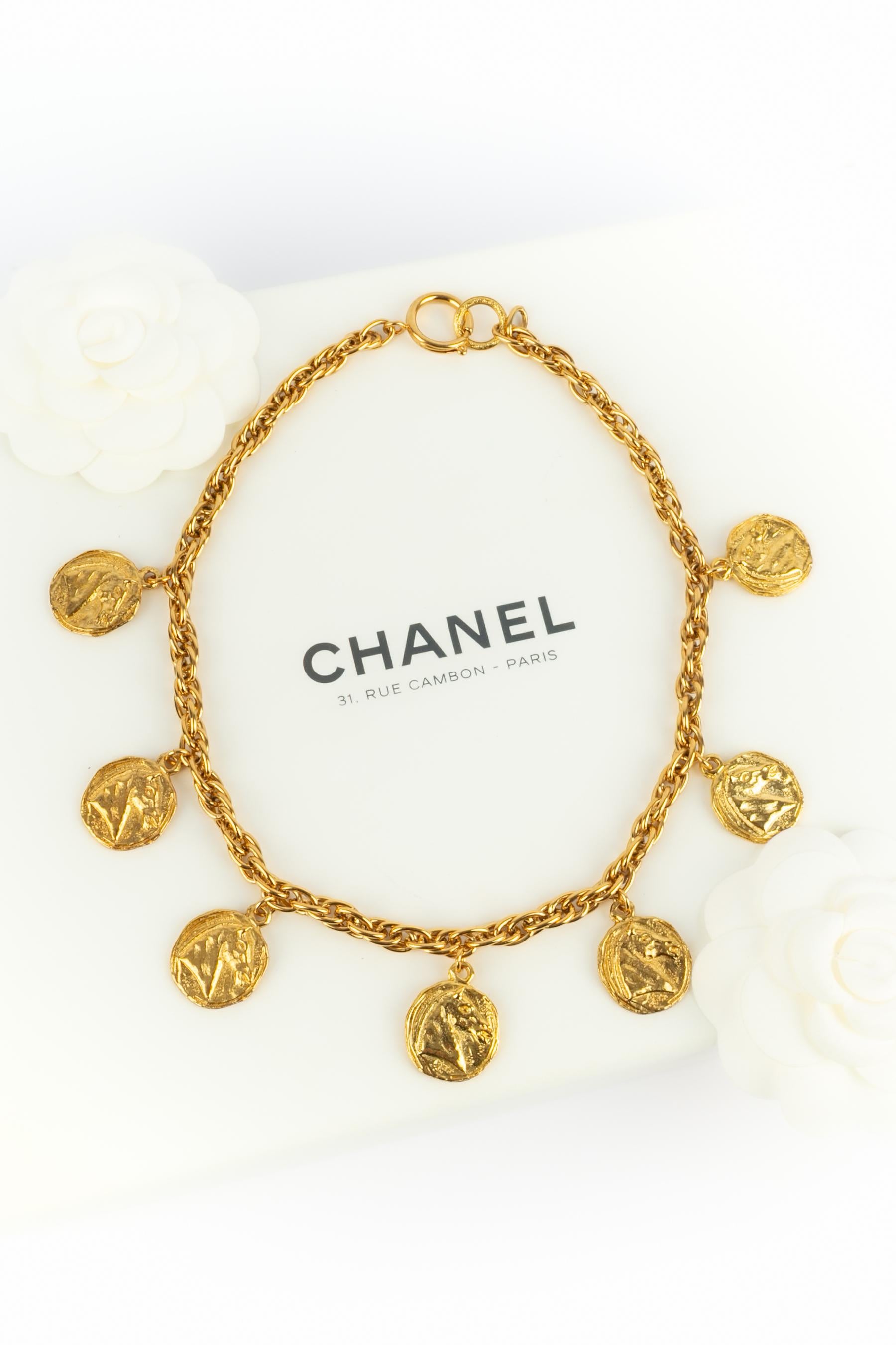 CHANEL - (Fabriqué en France) Collier court en chaîne de métal doré avec des pièces de monnaie en métal doré gravées.

Condit :
Très bon état.

Dimensions :
Longueur : 43 cm

SKU:CB114


