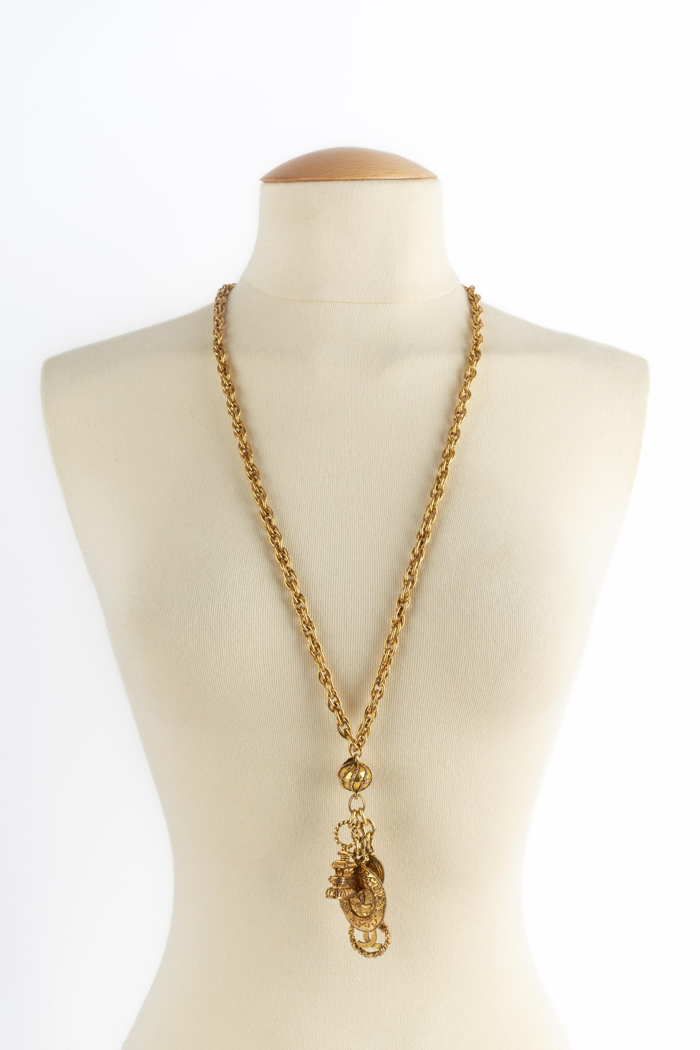 CHANEL - (Made in France) Goldene Metallkette mit Anhängern, die Siegel darstellen. Schmuckstücke aus der Mitte der 1980er Jahre.

Bedingung:
Sehr guter Zustand

Abmessungen:
Länge: 84 cm

SKU:CB160