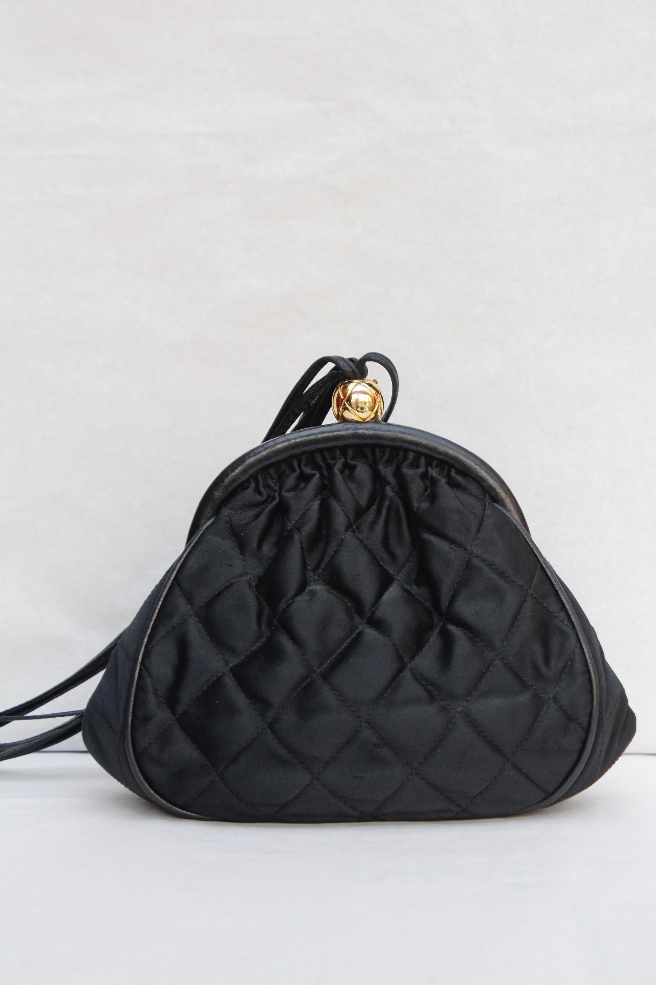 CHANEL (Made in Italy) Gorgeous small evening bag composed of quilted black satin, trimmed with leather edges. It opens with a gilded metal toggle closure in the shape of a quilted ball engraved with a CC logo. It can be worn cross-body or over the