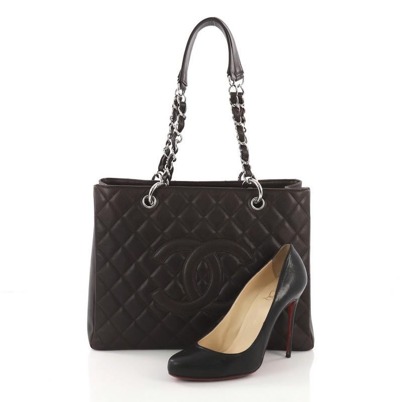 This Chanel Grand Shopping Tote Quilted Caviar, crafted in dark brown quilted caviar leather, features woven-in leather chain straps with leather pads, exterior back pocket, and silver-tone hardware. It opens to a brown fabric interior with two open