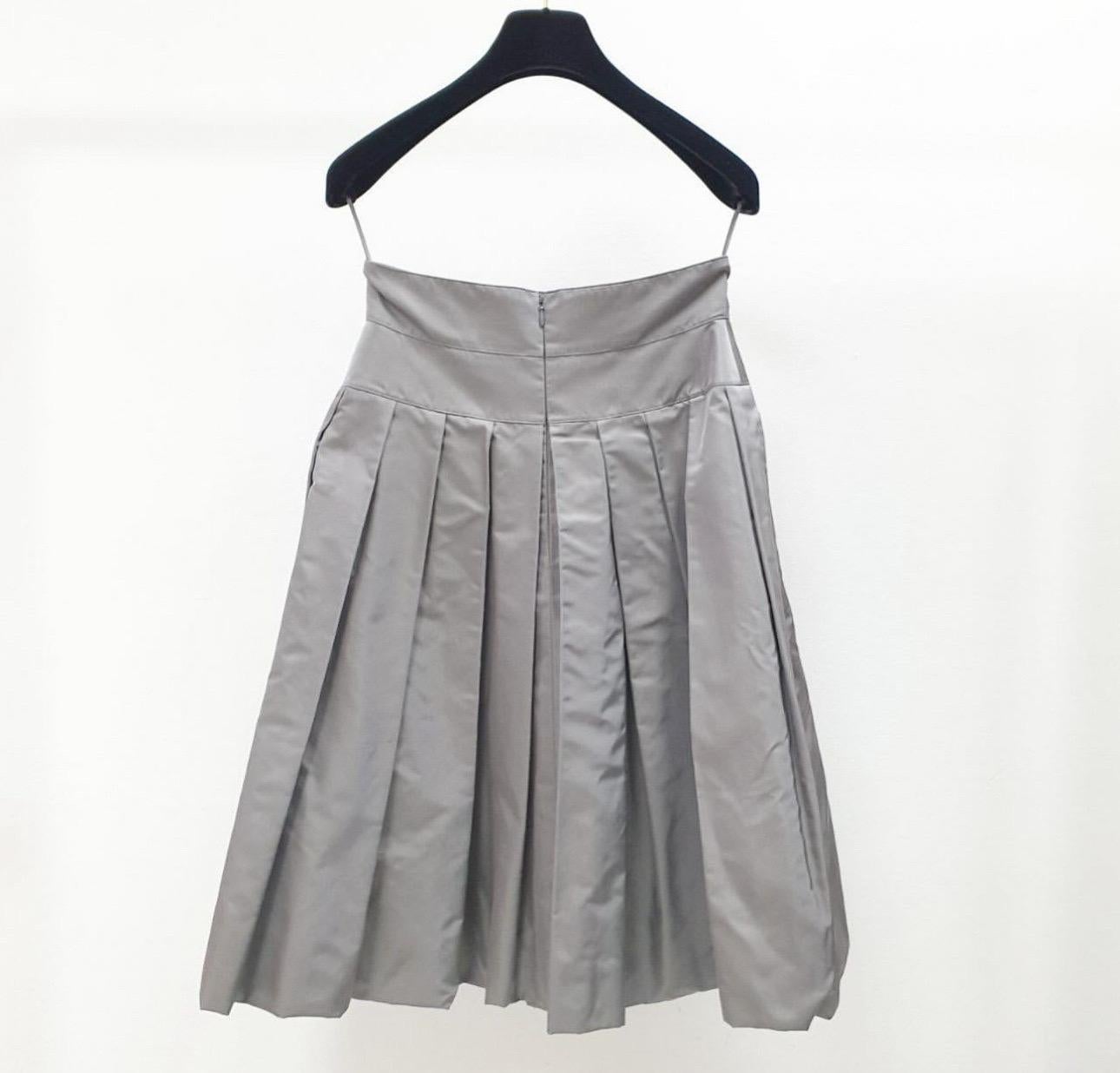 Eleganza della gonna al ginocchio in seta grigia Chanel taglia 38. Questa gonna è perfetta per ogni occasione, che sia una giornata in ufficio o una serata fuori. Il materiale in seta gli conferisce una sensazione di lusso e il taglio al ginocchio