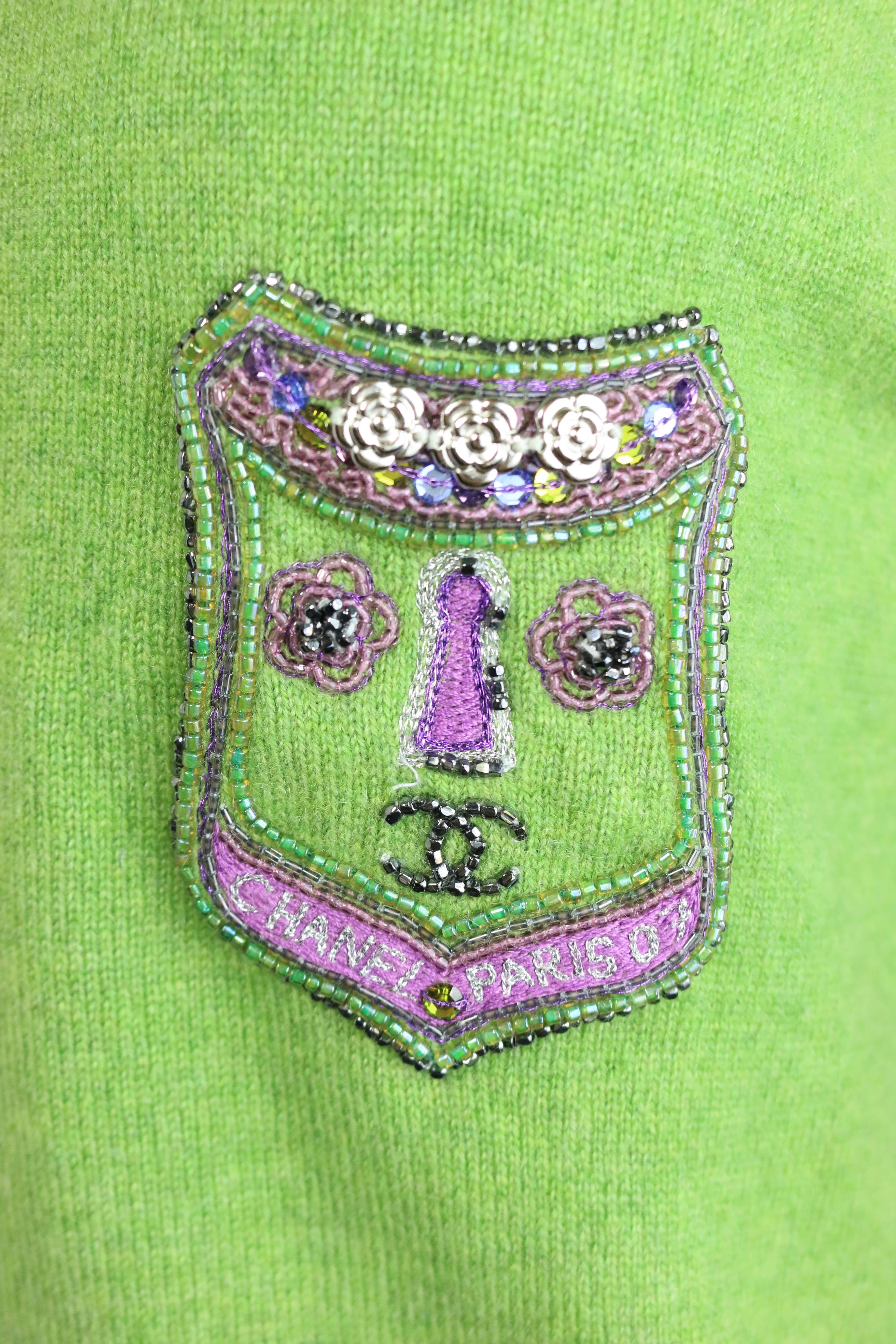 - Chanel green and purple cashmere pullover sweater from 2007 A/W Collection. Featuring  a patch in some signature Chanel camellia flowers hardware, beautiful sequins, embroidered that is written 