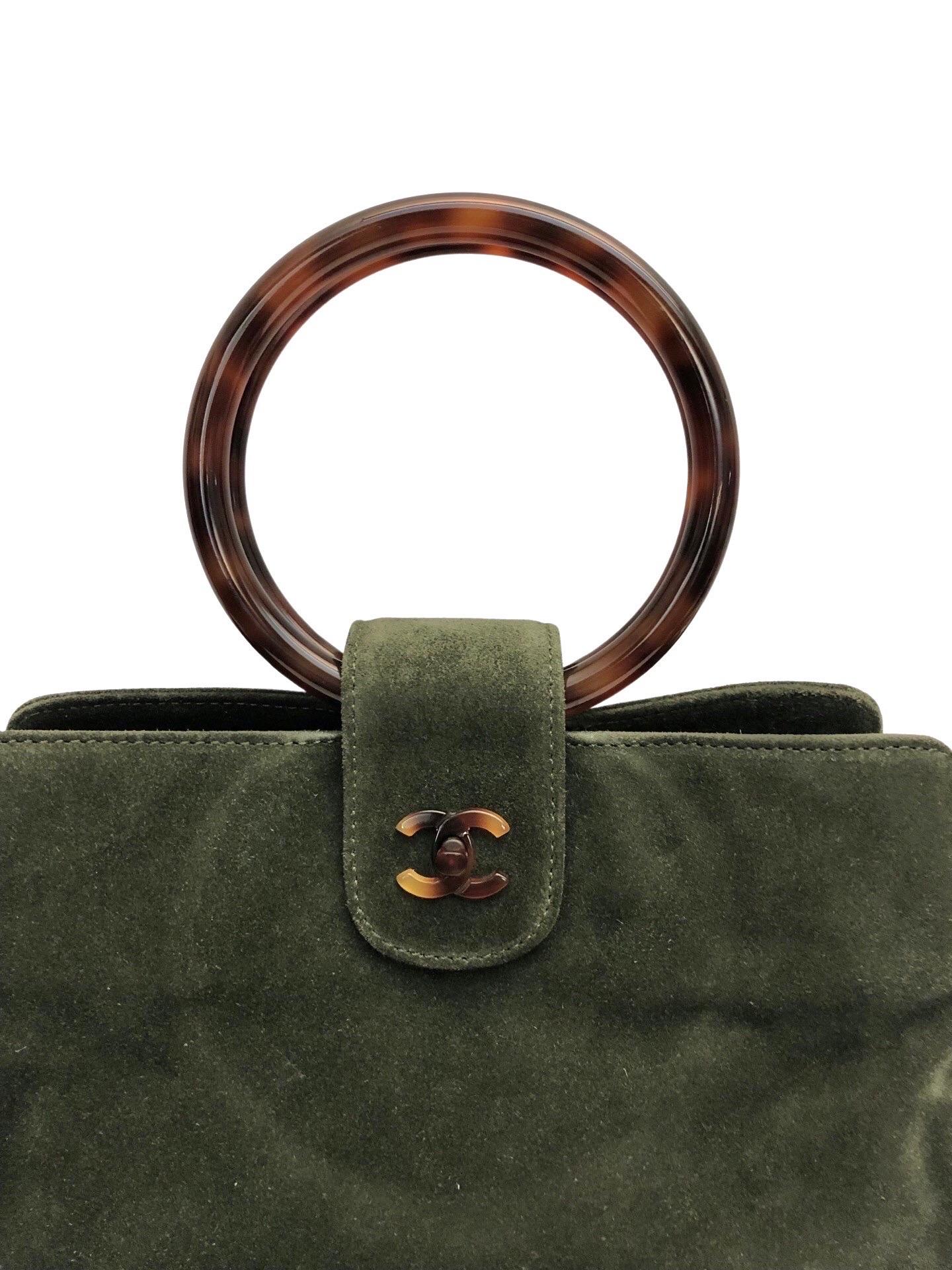 - Sac à main vintage Chanel des années 90 en daim vert avec anse en écaille. 

- Fermeture à clef tournante CC en écaille de tortue. 

- Trois compartiments. 

- Fermeture à glissière. 

- Deux poches intérieures zippées. 

- Longueur : 29 cm.