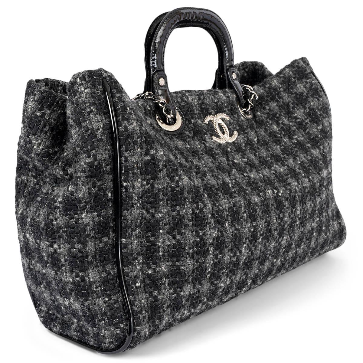 100% authentique Chanel shopper en tweed matelassé noir et gris avec poignées en cuir verni noir et bandoulière en chaîne. Le modèle s'ouvre par un bouton magnétique sur le dessus et est doublé de toile noire avec une grande poche zippée au dos et