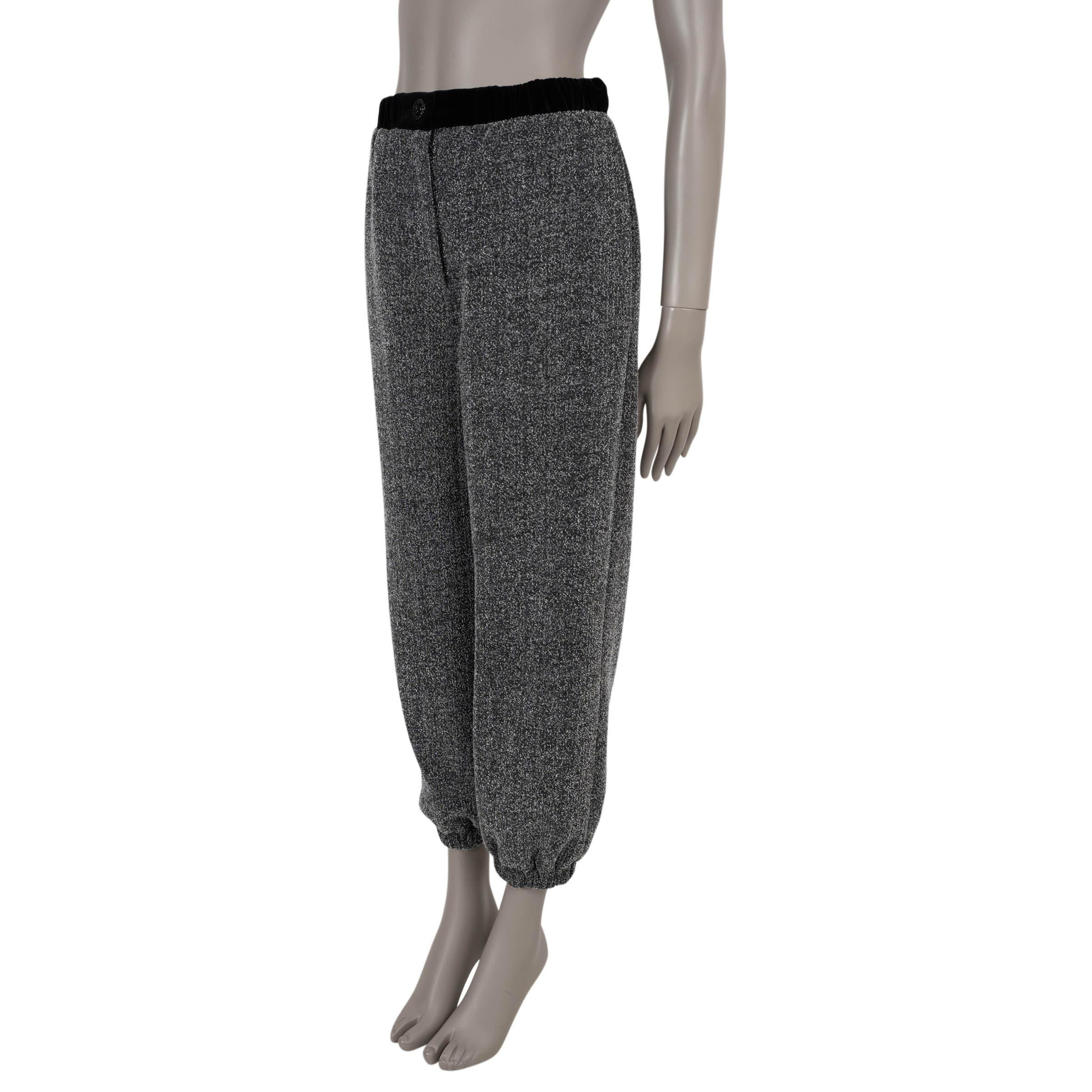 These 100% authentic Chanel track pants crafted from luxurious grey and white tweed in 100% cotton. Designed for effortless elegance, they feature a black velvet elastic waistband, a black enamel CC-embellished button, and slit pockets on the sides