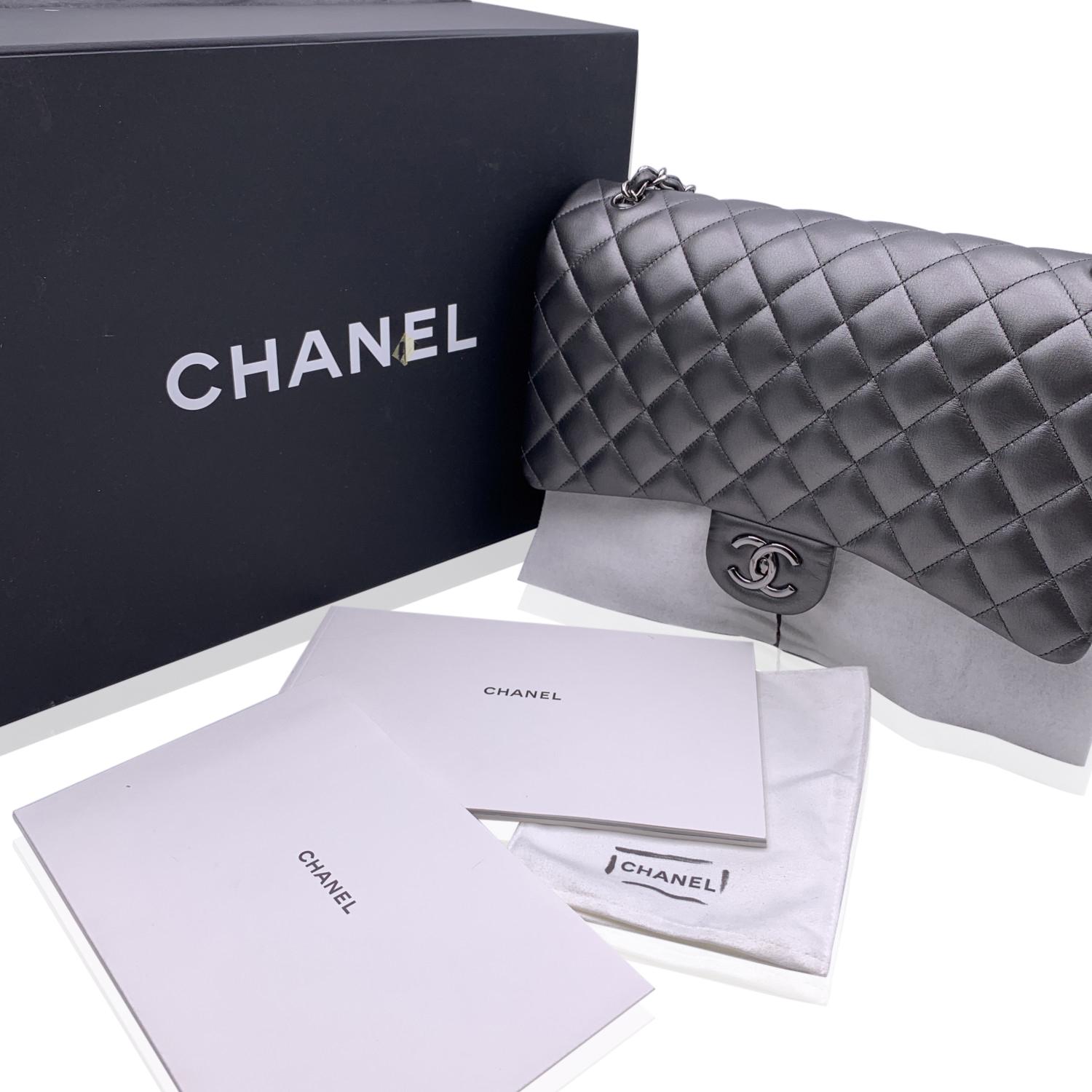 Chanel 'Maxi' Classic Quilted Double Flap Bag. Grey metallic quilted leather. Silver metal hardware. Period/Era: 2013/2014. It features double 'CC' turn lock closure and double flap interior. Interwoven chain/leather strap; can be worn on the