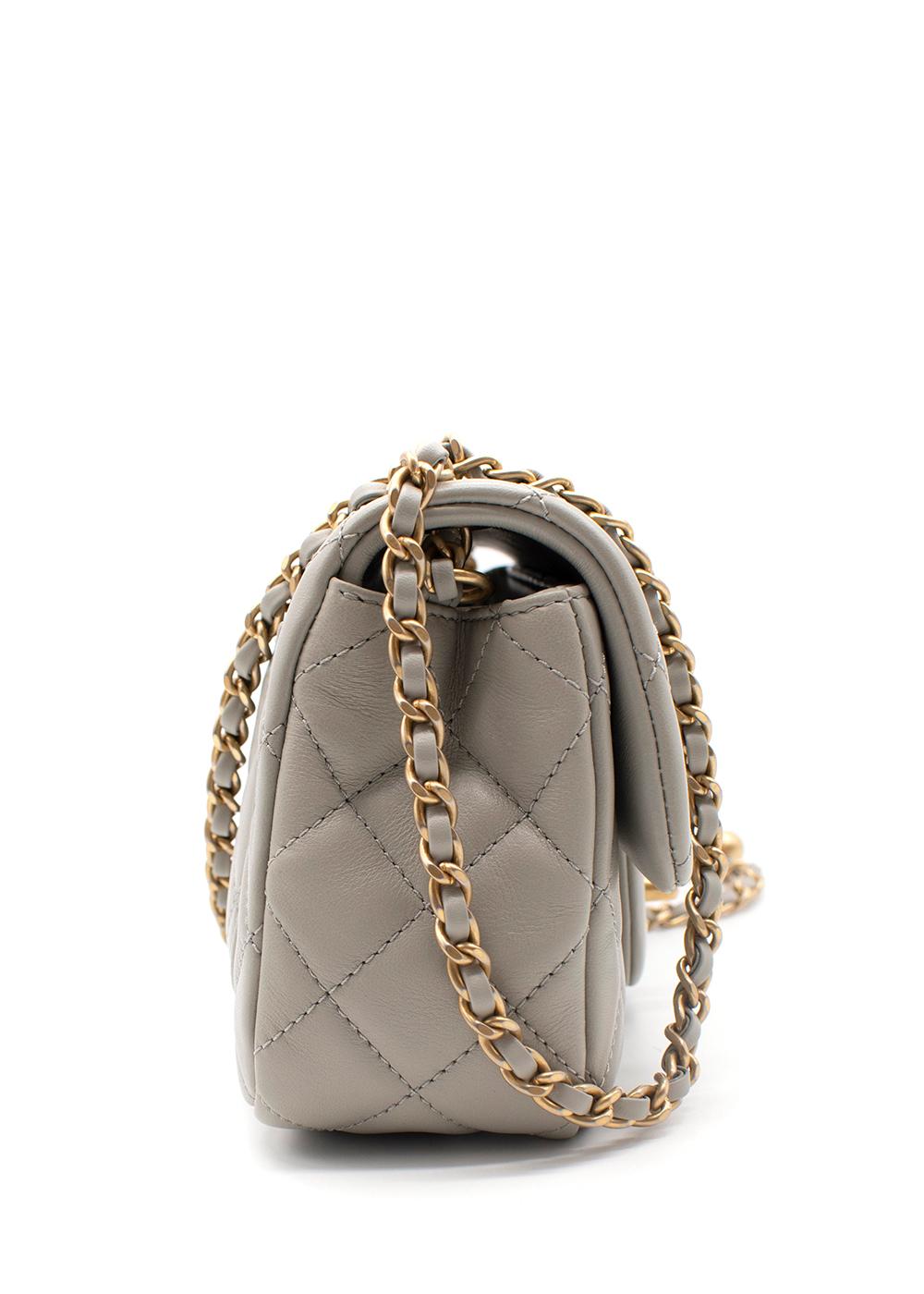 Chanel Grey Quilted Pearl Crush Mini Flap Bag

- Soft lambskin body in a warm pearl grey hue with signature diamond quilting 
- Flap top with CC turnlock closure 
- Leather and chain strap with decorative faux gold-tone metal orb
- Opens to