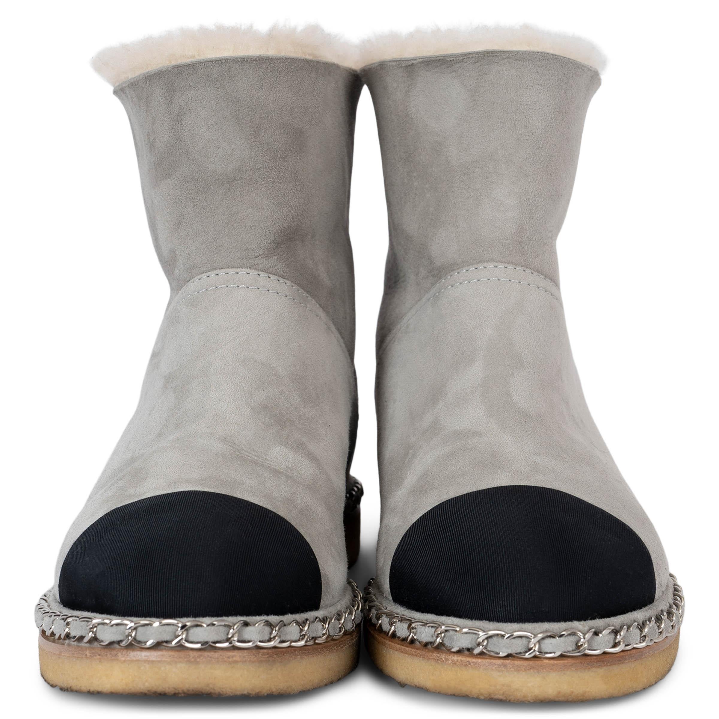 Ces bottes doublées de shearling 100% authentiques de Chanel sont confectionnées en daim gris luxueux, offrant à la fois style et confort. Doté du bout en gros-grain noir classique de Chanel, chaque orteil est bordé d'une chaîne argentée signature,