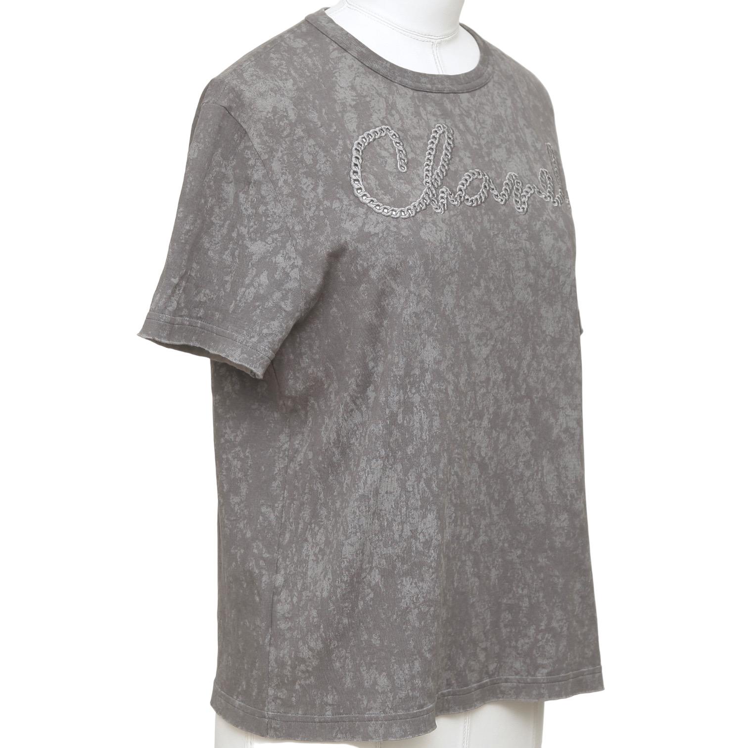 GUARANTEED AUTHENTIC CHANEL 2020 SIGNATURE GREY TIE-DYE T-SHIRT

Design:
- Grey color tie-dye design t shirt.
- Signature accent at front.
- Crew neck.
- Short sleeve.
- CC plaque at left shoulder.
- Slip on.

Size: 34/36

Material: 100%