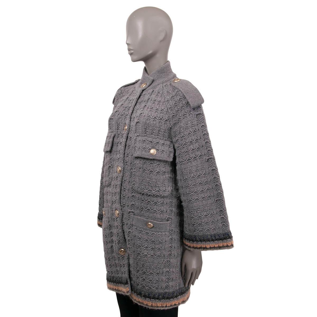 100% authentic Chanel oversized chunky knit coat in grey wool (90%) and cashmere (10%) with breaded trims in charcoal, nude, grey, navy and silver lurex. The design features wide 3/4 sleeves, a stand-up collar, two chest flap-pockets, two front