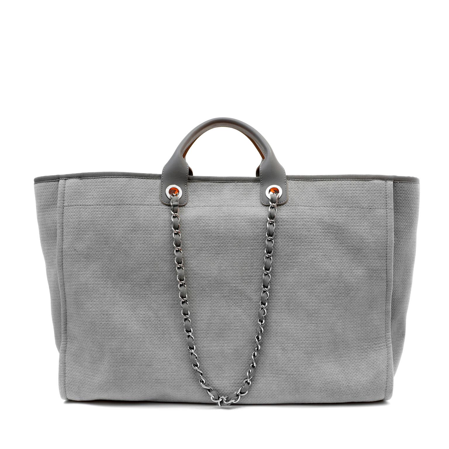 This authentic Chanel Grey XXL Deauville Tote is in pristine condition.  The iconic Chanel design is perfect for resort wear and travel.
Dark grey fabric tote is extra large and roomy.  Silver stitching and hardware.  Carried by the leather top