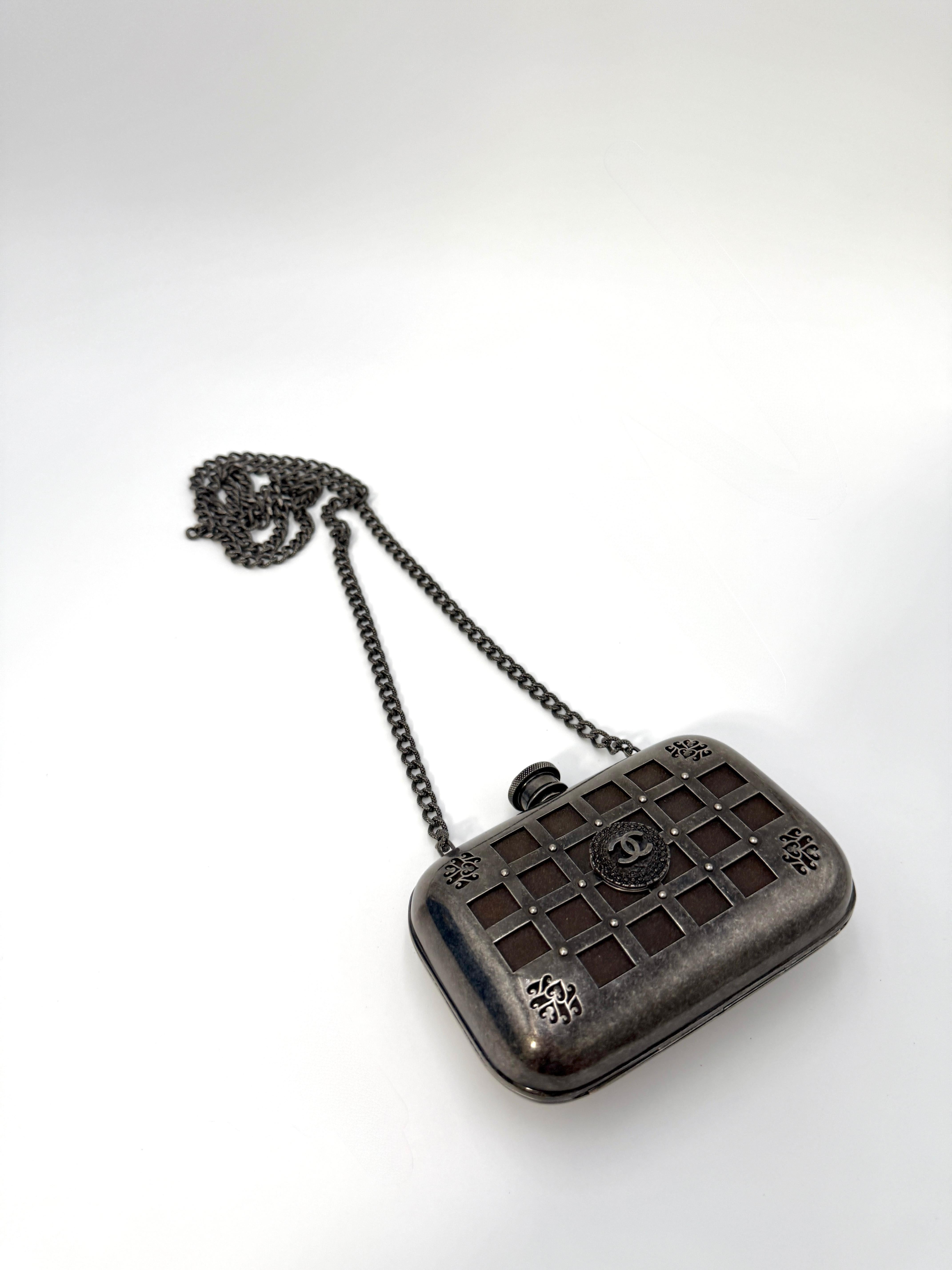 Cette rare minaudière Chanel Grid Cage est réalisée en métal argenté vieilli avec un treillis complexe et des accents décoratifs dans les coins, centrés par le médaillon du logo CC classique. Ce modèle est doté d'un bouchon à vis inspiré des flacons