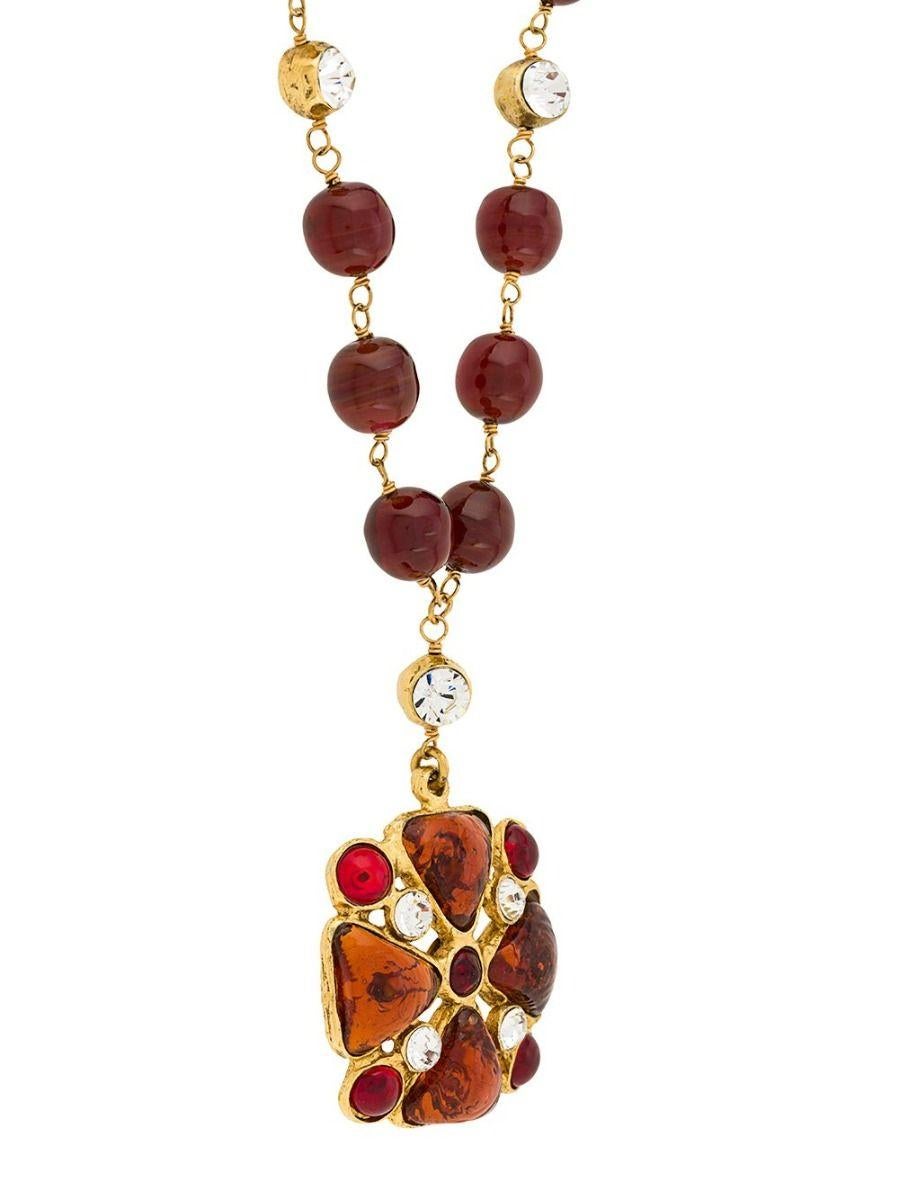 Circa 2009, this vintage gripoix necklace from Chanel was meticulously crafted in France from yellow-gold-plated metal, round ruby red and amber-coloured glass beads, and a statement-making crystal pendant embellishment in the shape of the maltese