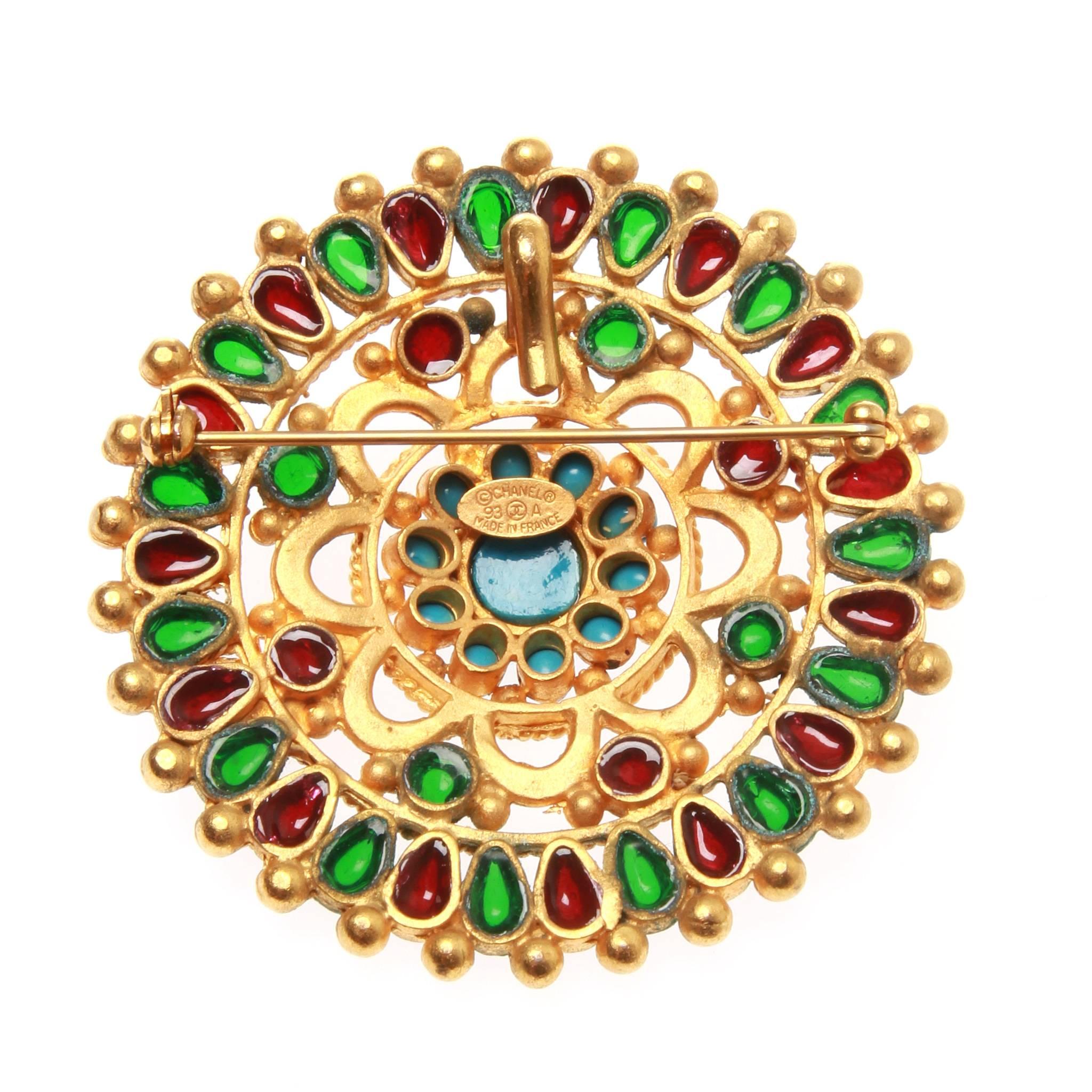 A fabulous rare Chanel massive brooch/pendant.

Open work matte gold tone metal embellished with faux precious GRIPOIX cabochons : turquoise, ruby and emerald.

Production year: Fall 1993 collection

Comes with box