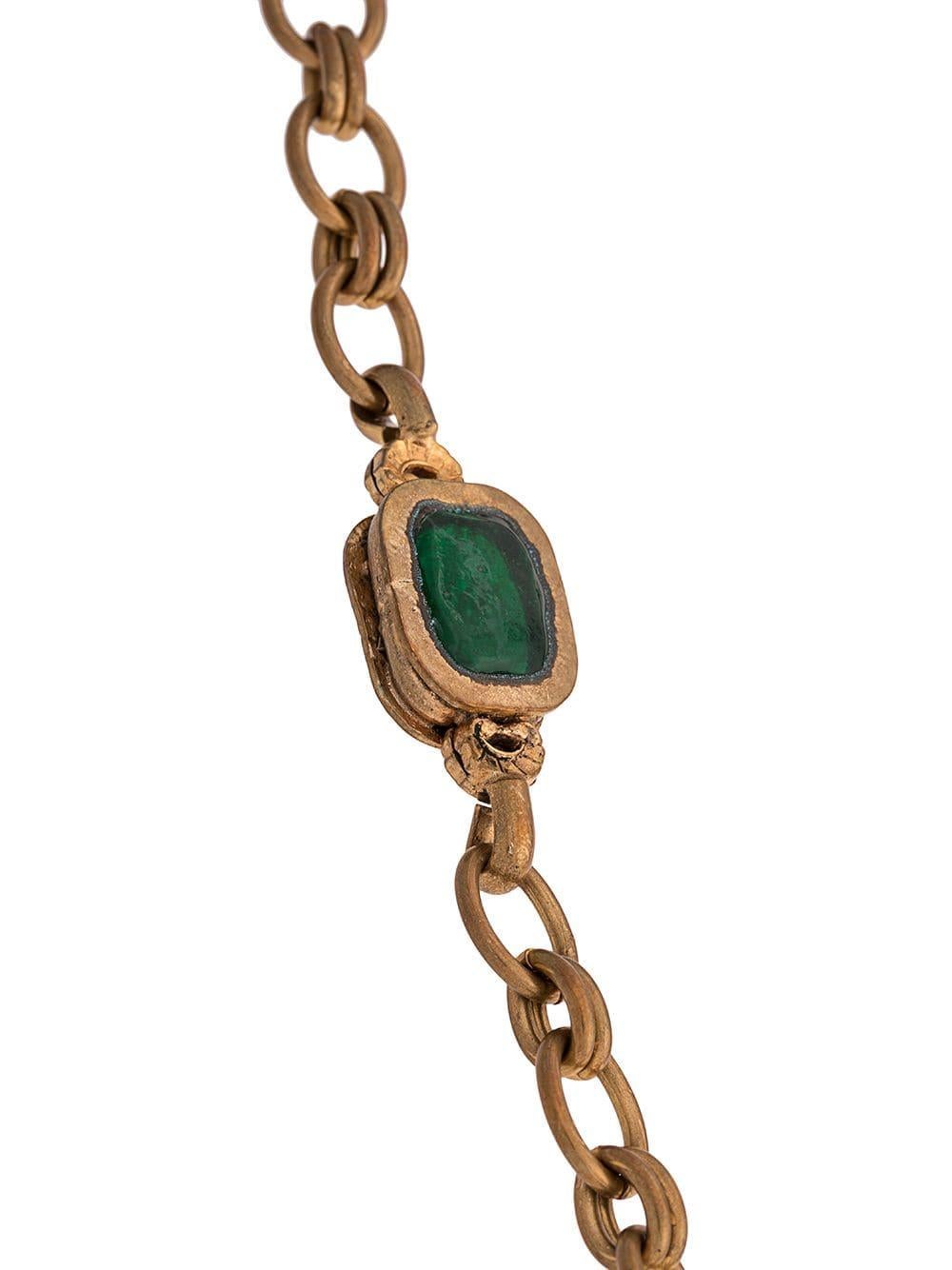 Crafted in France, this elegant, pre-owned necklace from Chanel is a unique piece that adds a touch of classic sophistication to any outfit and features an intricate combination of antique gold-toned brass hardware, ruby red and green gripoix glass