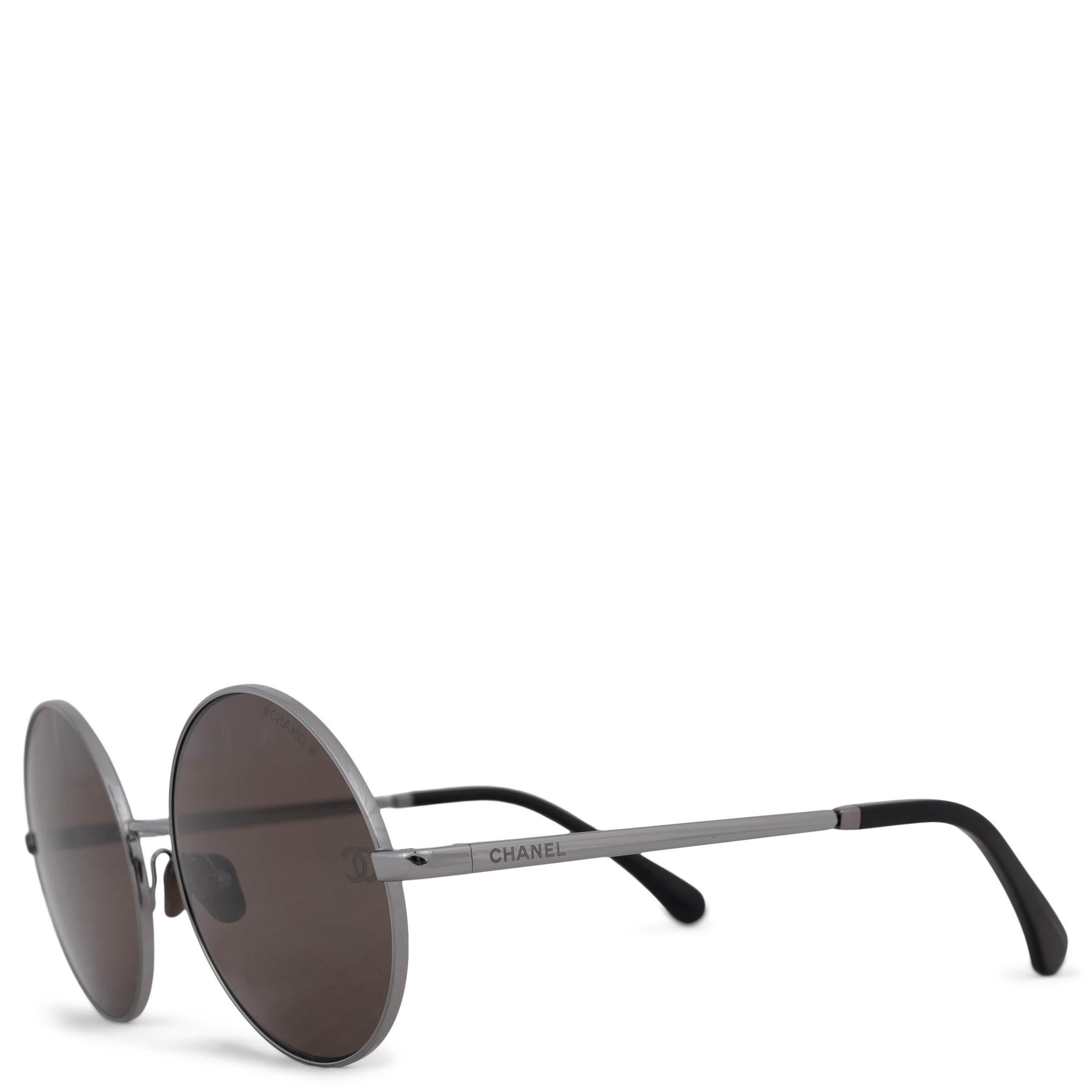 Diese 100% authentische Chanel Sonnenbrille aus Titan in Gunmetal strahlt moderne Eleganz aus. Mit ihrem schlanken, runden Rahmen und den braunen Gläsern ist sie mit dem Schriftzug am Bügel und den schwarzen Bügelenden versehen und verbindet