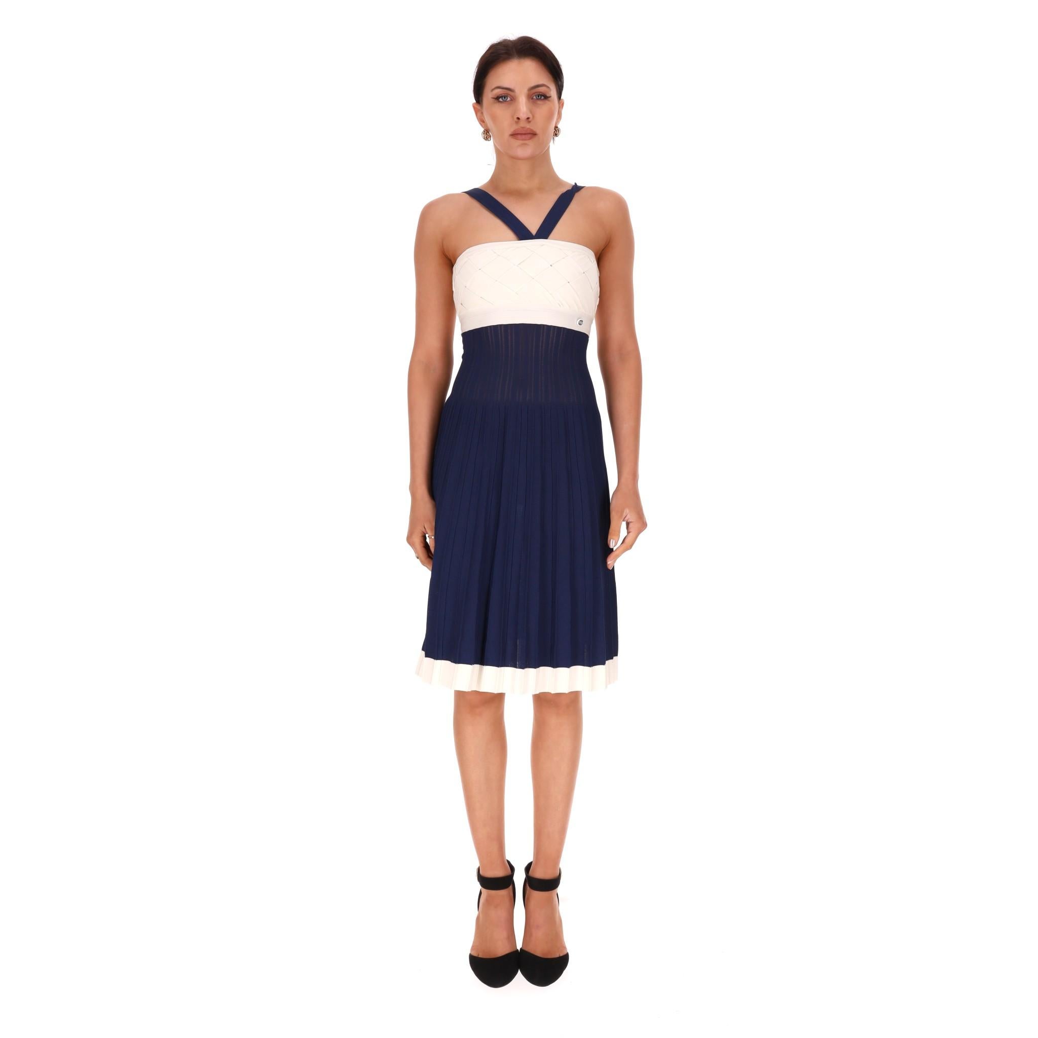 Chanel - Vestito con aletta e cardigan con bolero

Abito al ginocchio senza maniche di colore navy con scollo a spallina.

Whiting: top bianco, ampia vita elasticizzata e gonna a pieghe con bordi bianchi.

Dettagliato con placca 
