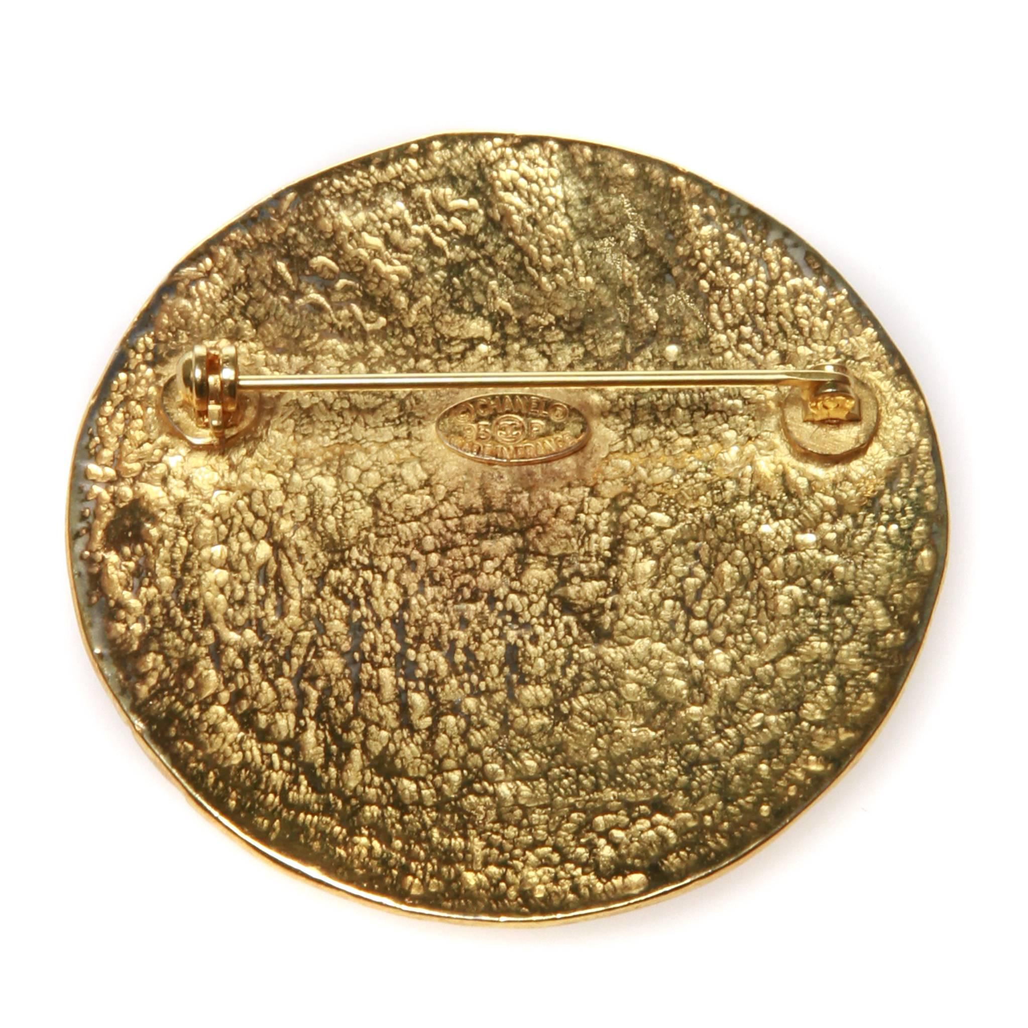Chanel brooch featuring a gold-tone hammered finish disc embossed with the interlocking CC. 

Stamped 95 P - Spring/Summer 1995