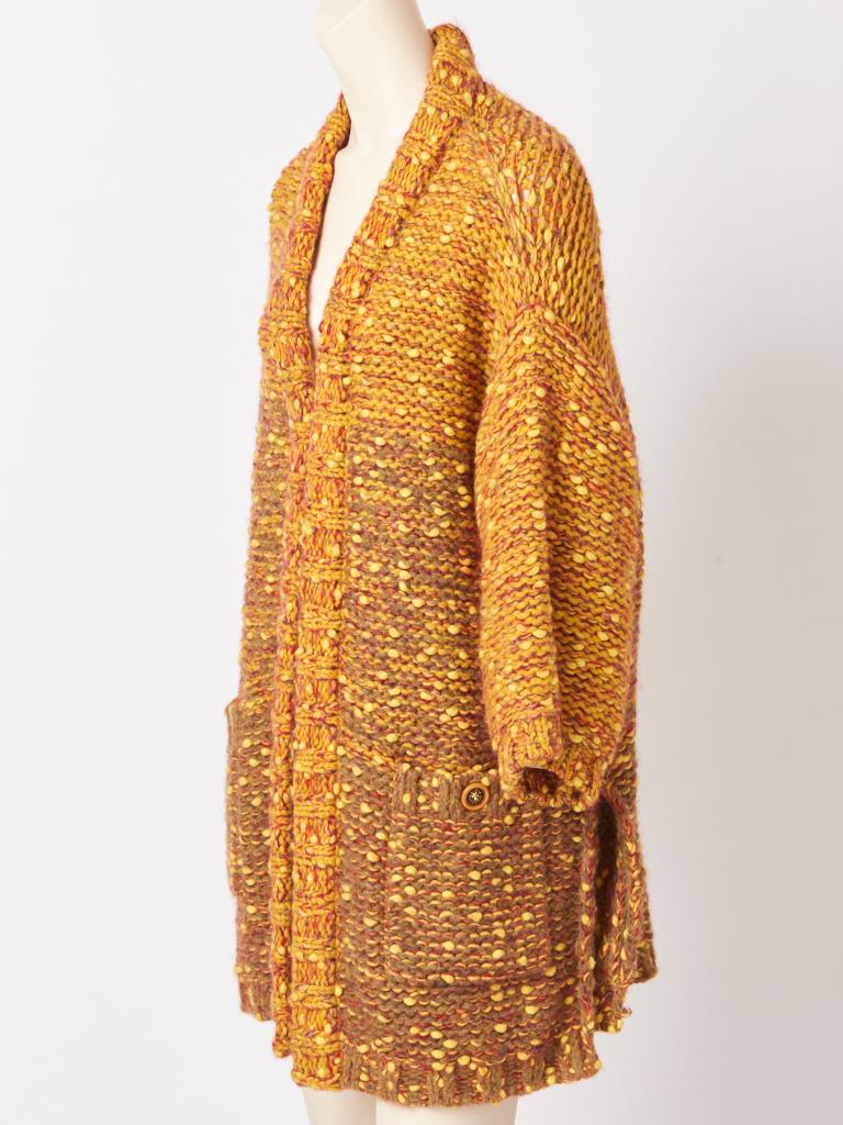 Chanel, handgestrickte, lange Strickjacke mit aufgesetzten Taschen und Seitenschlitzen in bunten Farbtönen  von Ocker und Orange. 