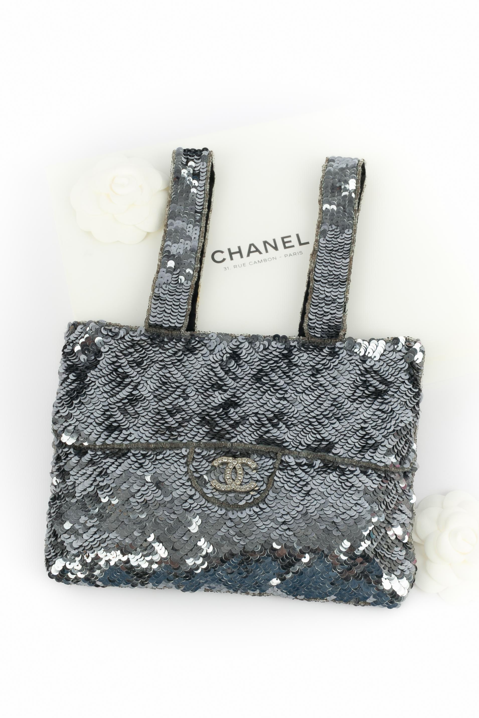 CHANEL - (Made in France) Graue 'Trompe L'Oeil' Tasche aus Pailletten mit schwarzem Seidenfutter. Stück mit der Seriennummer 5537947.

Bedingung:
Sehr guter Zustand

Abmessungen:
Höhe: 16 cm - Breite: 22 cm - Tiefe: 1 cm - Griffe: 28 cm

SKU:S36