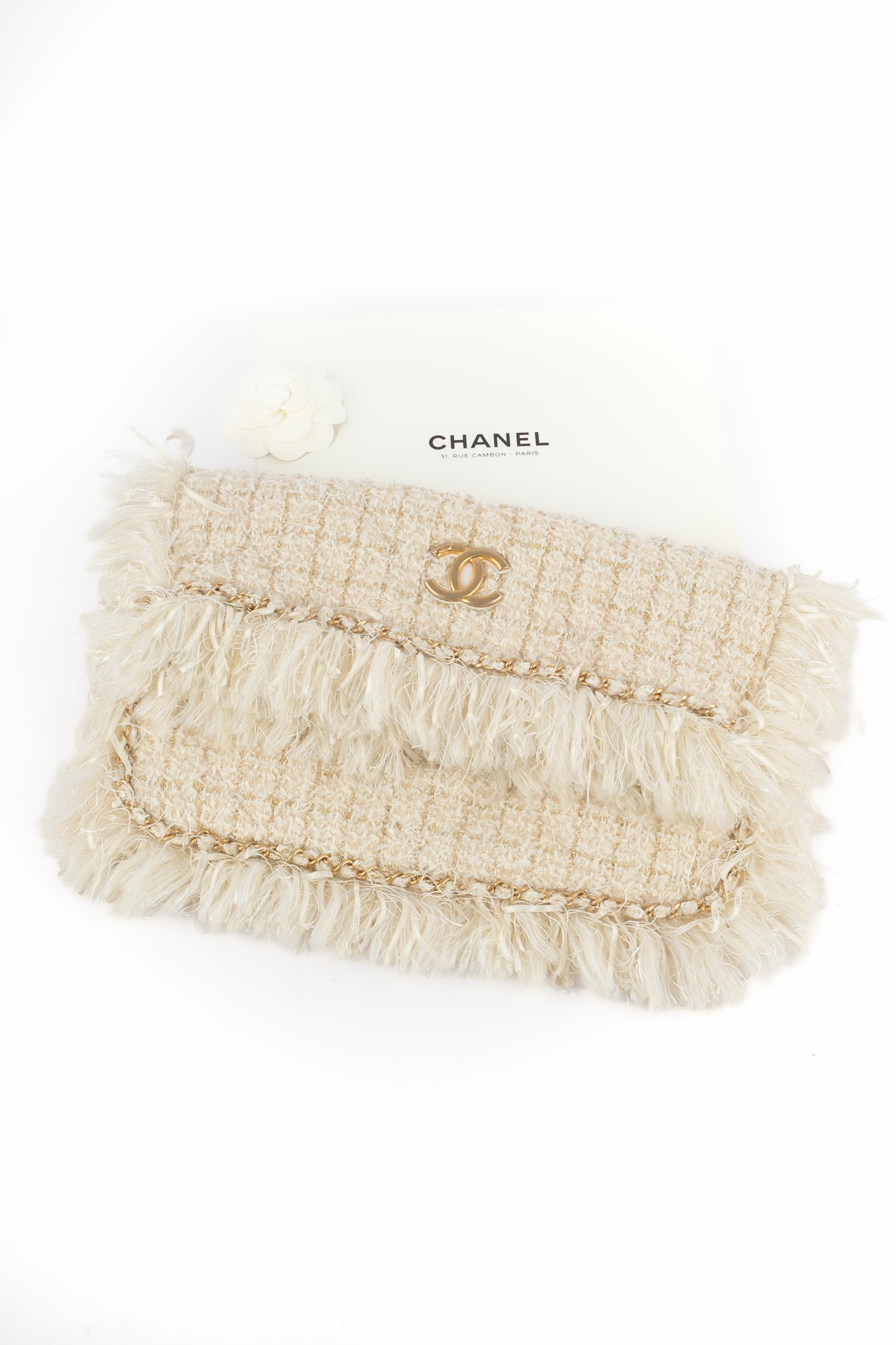 CHANEL - (Made in Italy) Gesteppte, cremefarbene Tweed-Handtasche mit Lurexfäden, die mit Fransen und einer verflochtenen goldenen Metallkette verziert ist. Magnetischer Druckknopf auf einer Klappe mit den Hauskennzeichen in matter Ausführung. Stück
