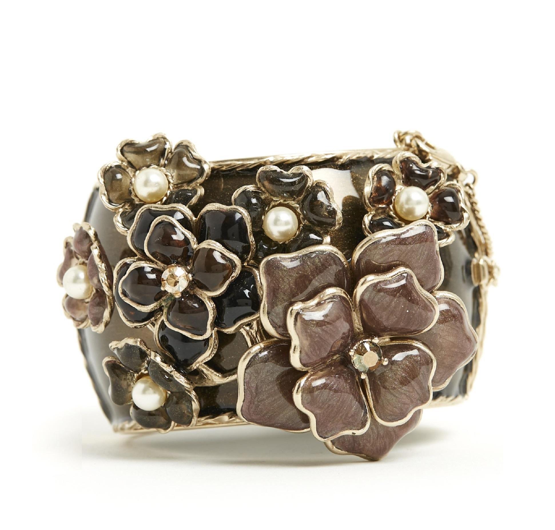 Chanel cuff bracelet in gold metal covered with brown enamel decorated with a large CC in enameled metal on one side and a large floral pattern in glass paste decorated with white rhinestones and fancy pearls, magnetic closure lined with a hook and