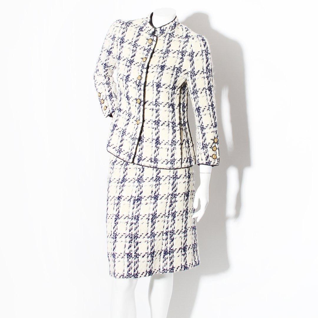 Product Details:
Haute couture houndstooth suit by Chanel
Circa 1960's
Creme and blue tweed suit  
Navy trim
Two side pockets on jacket
Mandarin style collar
Gold tone hardware
Button front closure  
Button cuff closure 
Floral buttons 
Purple