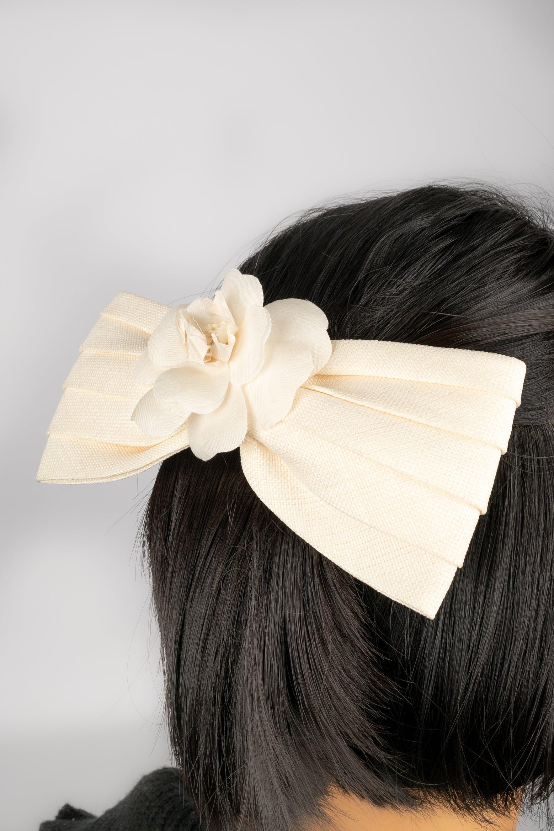 Chanel - (Made in France) Hair clip representing a cream color bow decorated with a camellia.
 
 Additional information: 
 Condition: Good condition
 Dimensions: Length: 18 cm
 
 Seller Reference: ACC16
