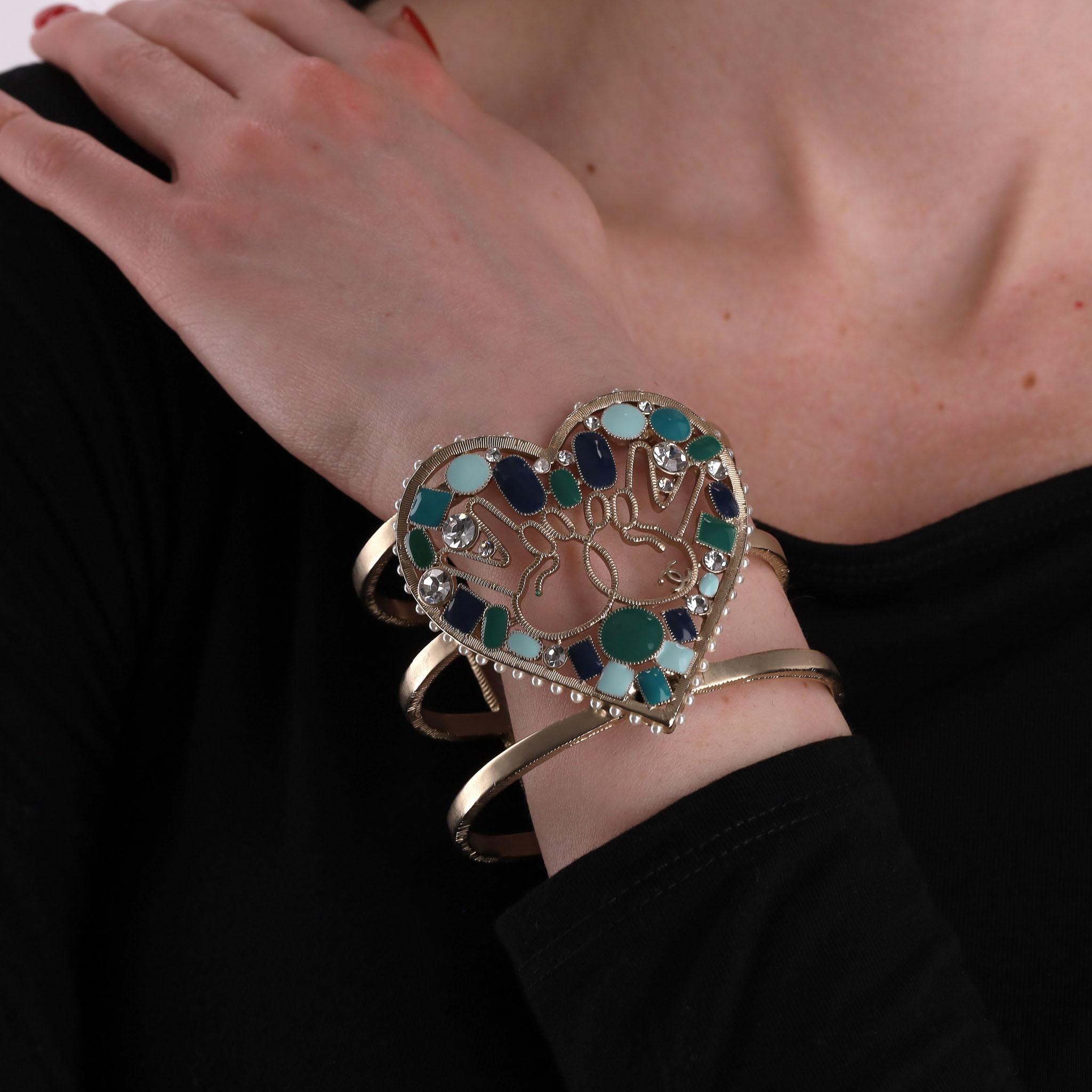 Rare Piece - Chanel Heart-Shaped Enamel, Pearl & Swarovski Crystal Peace Cuff Bracelet

Champagne gold heart-shaped cuff bracelet trimmed with tiny resin pearls.

Designed with Peace symbol to the centre of the heart with multiple enamel stones in