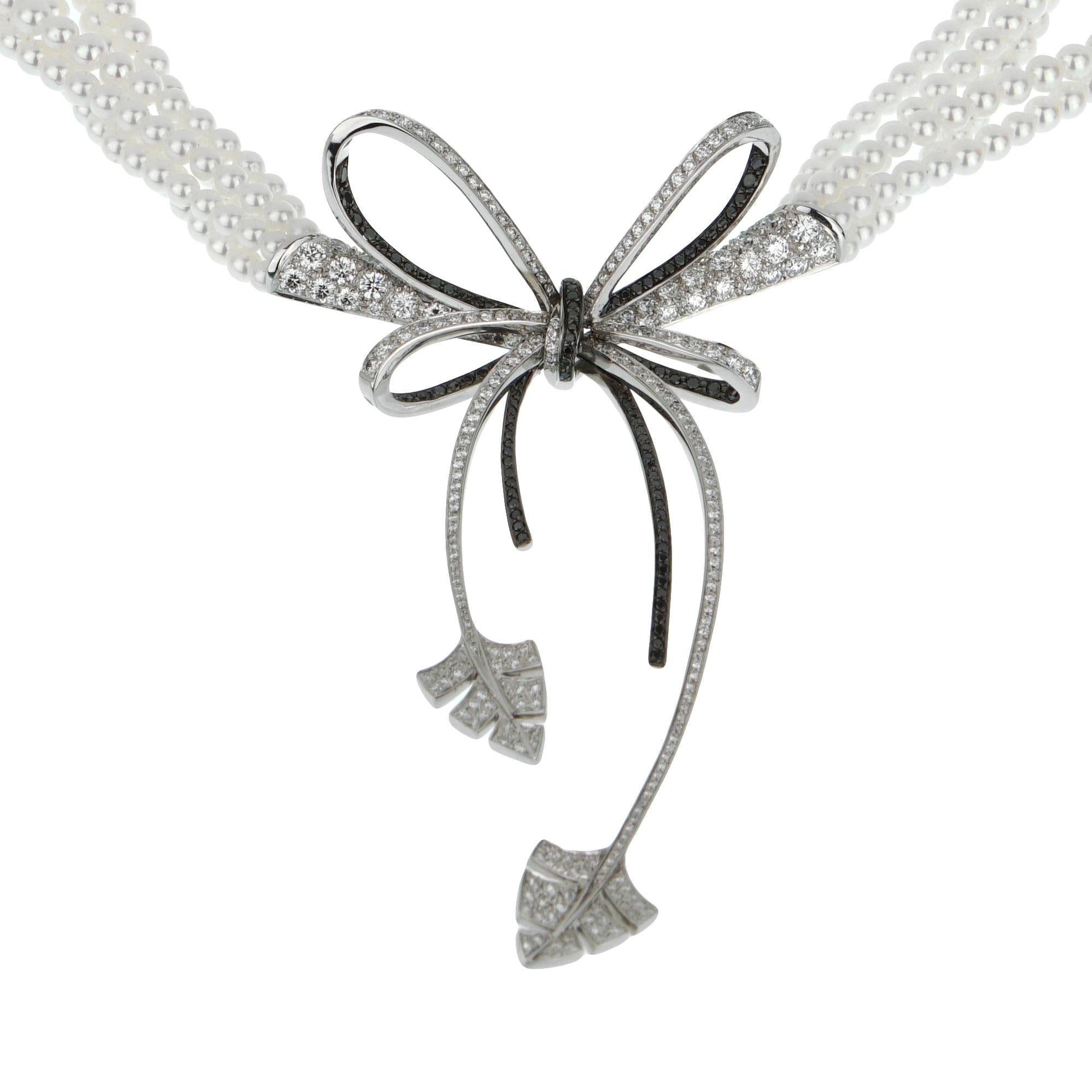 A magnificent brand new Chanel pearl diamond necklace showcasing a delicate bow incorporating brilliant white and black diamonds in 18k white gold. The necklace is suspended by 5 pearl strands and a matching decorated locking mechanism encased with