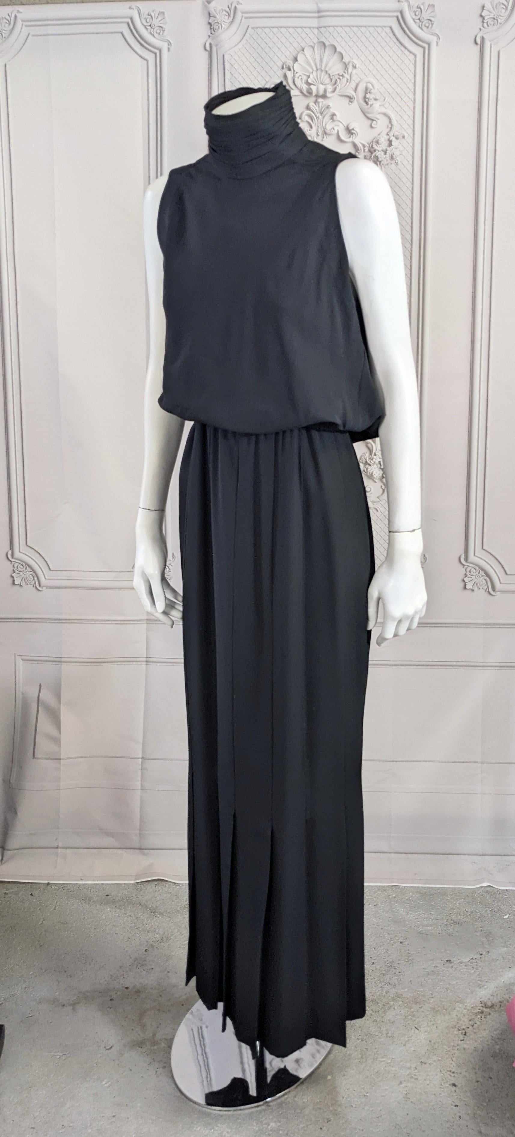 Iconic Chanel High Neck Column Heavy Silk Crepe Gown from the 1980's by Karl Lagerfeld. High collar is ruched, pleated and fastened with CC logo buttons. One piece gown with sleeveless blouson bodice with long tucks on skirt which release to pleats
