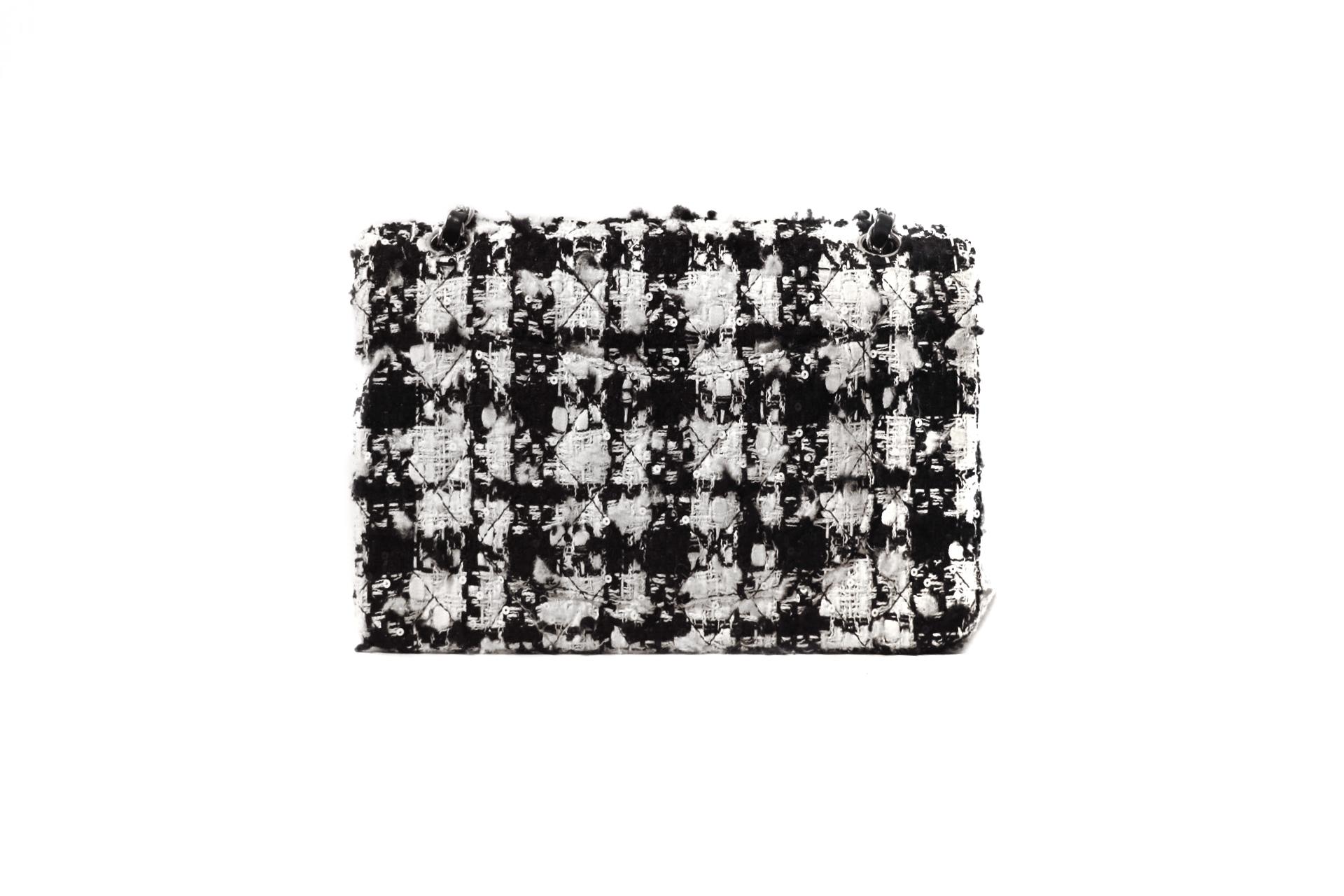 This authentic Chanel Houndstooth Double Flap Bag is in mint condition.  The medium silhouette paired with the classic tweed pattern makes this an irresistible piece for any collector. Spring 2005 Collection.   
Black and white tweed fabric in