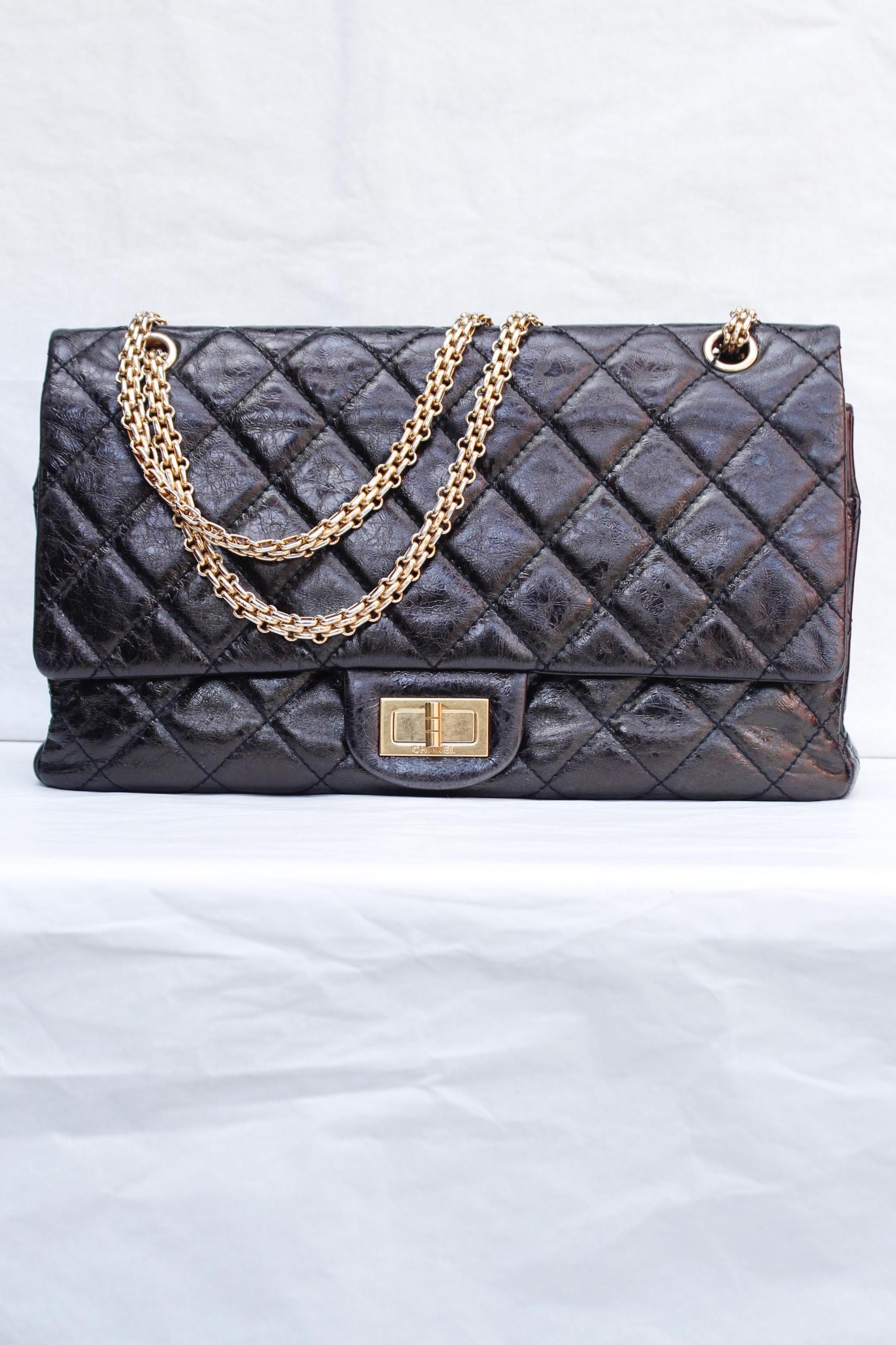 CHANEL (Made in France) Iconic 2.55 bag in brown/black cracked patent leather, with gilded metal hardware. It can be worn over the shoulder or cross-body with its long sliding chain. One patch pocket in the back. Twist lock closure.

The first flap