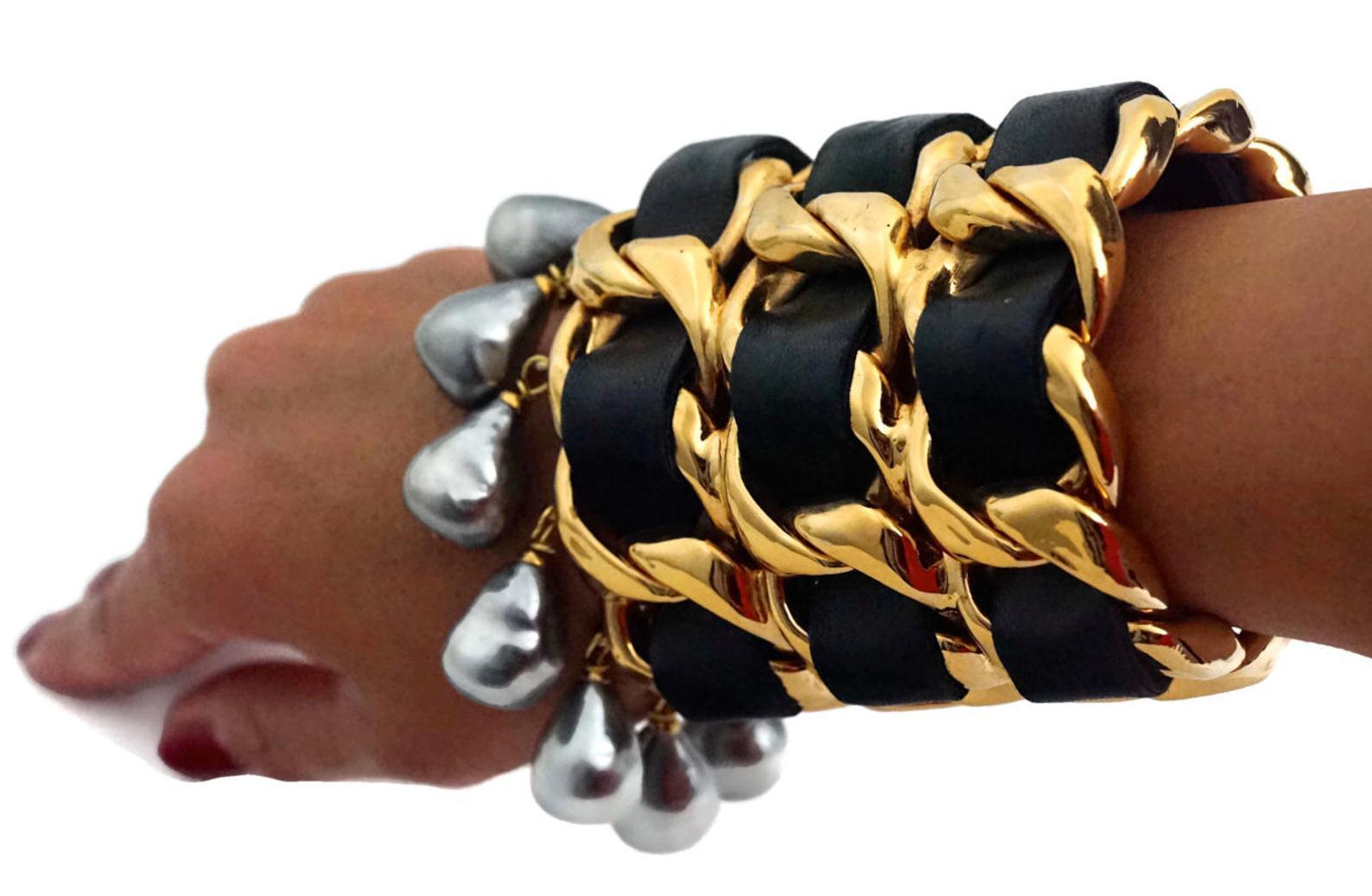CHANEL Iconic Triple Chain Leather Pearl Drop Cuff Bracelet

Measurements:
Height: 4 4/8 inches
Opening: 1 2/8 inches
Inside Circumference: 7 inches

Features:
- 100% Authentic CHANEL.
- Chunky 3 tiered woven chain and black leather.
- Dangling