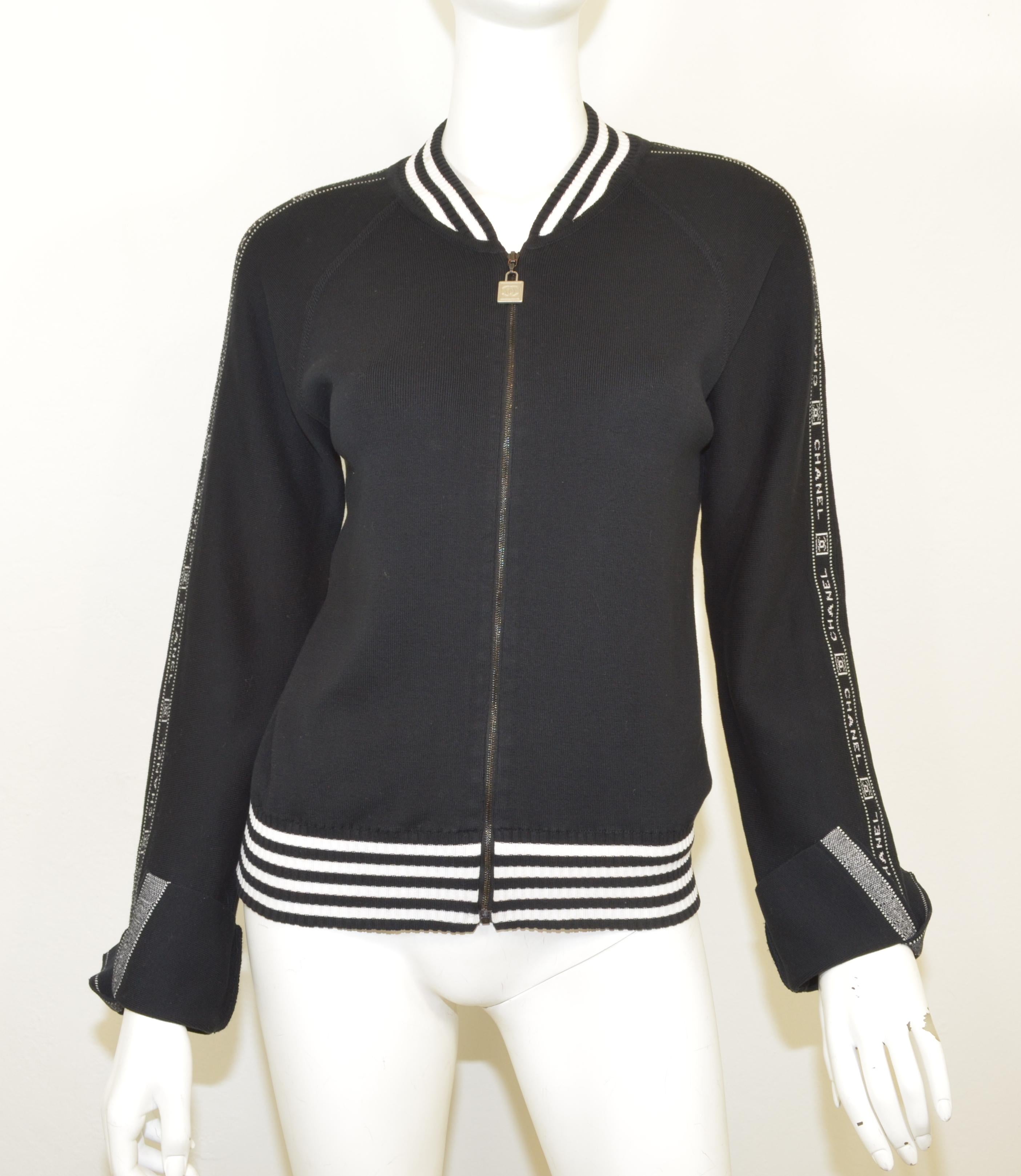 Chanel Identification 100% cotton logo black and white track jacket from 2004. Stretch knit black zip front with a CC padlock zipper pull. White CHANEL CC ribbon trim down the sleeves. Black and white striped ribbed waistband and neck. Long sleeves