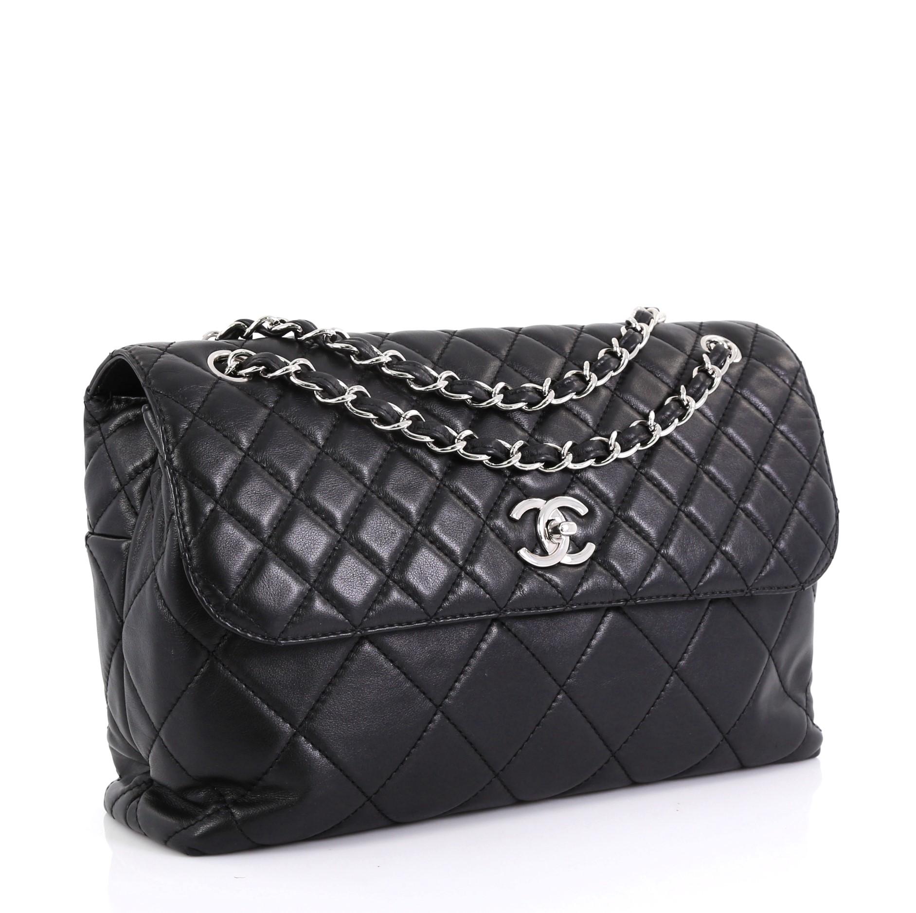 This Chanel In The Business Flap Bag Quilted Lambskin Maxi, crafted from black quilted lambskin leather, features dual woven-in leather chain straps, exterior back pocket, and silver-tone hardware. Its CC turn-lock closure opens to a black fabric