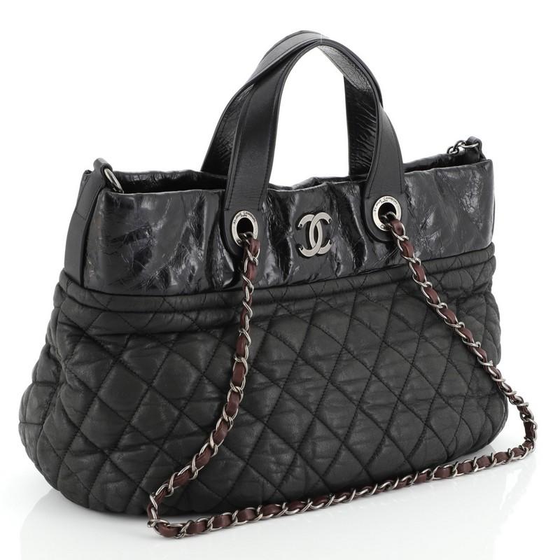This Chanel In The Mix Tote Quilted Iridescent Calfskin Large, crafted from black quilted iridescent calfskin leather, features flat leather handles, woven-in leather chain straps, CC logo at front, and aged silver-tone hardware. Its magnetic snap