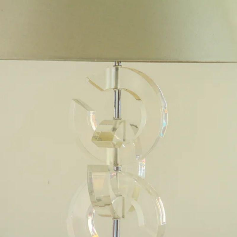 A single 'Chanel' inspired lucite table lamp with three interlinked 'C's stacked around a nickel stem on a square lucite base, 1970s.

Light cracking to the lucite.

Additional Information:
Material: Lucite, Nickel
Dimensions: 49 D x 49 W x
