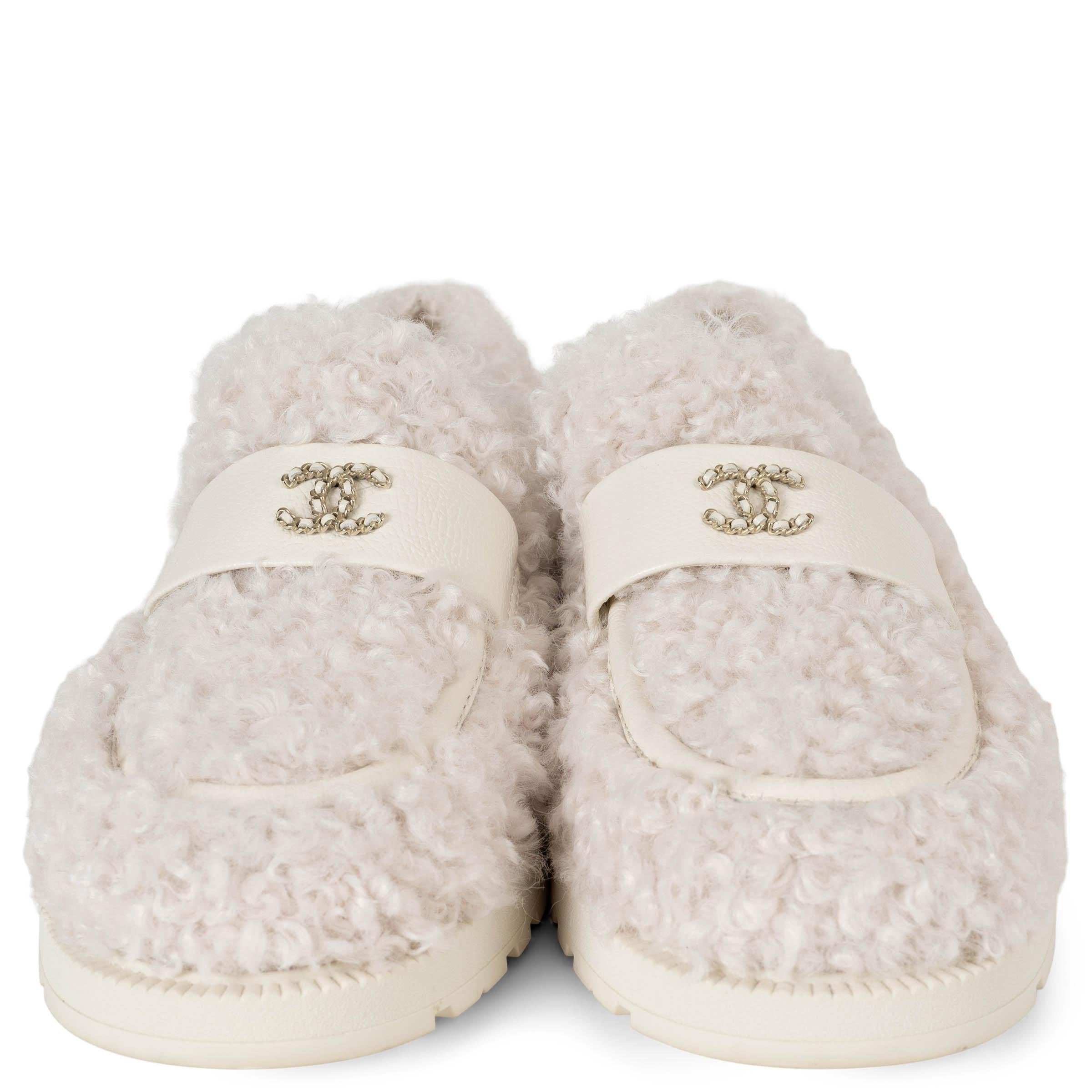 Diese 100% authentischen Chanel 2024 Coco Neige Shearling Loafers in Creme sind die perfekte Mischung aus Luxus und Komfort. Aus plüschigem Shearling gefertigt und mit dem charakteristischen CC-Kettenlogo auf der Vorderseite versehen, verkörpern sie