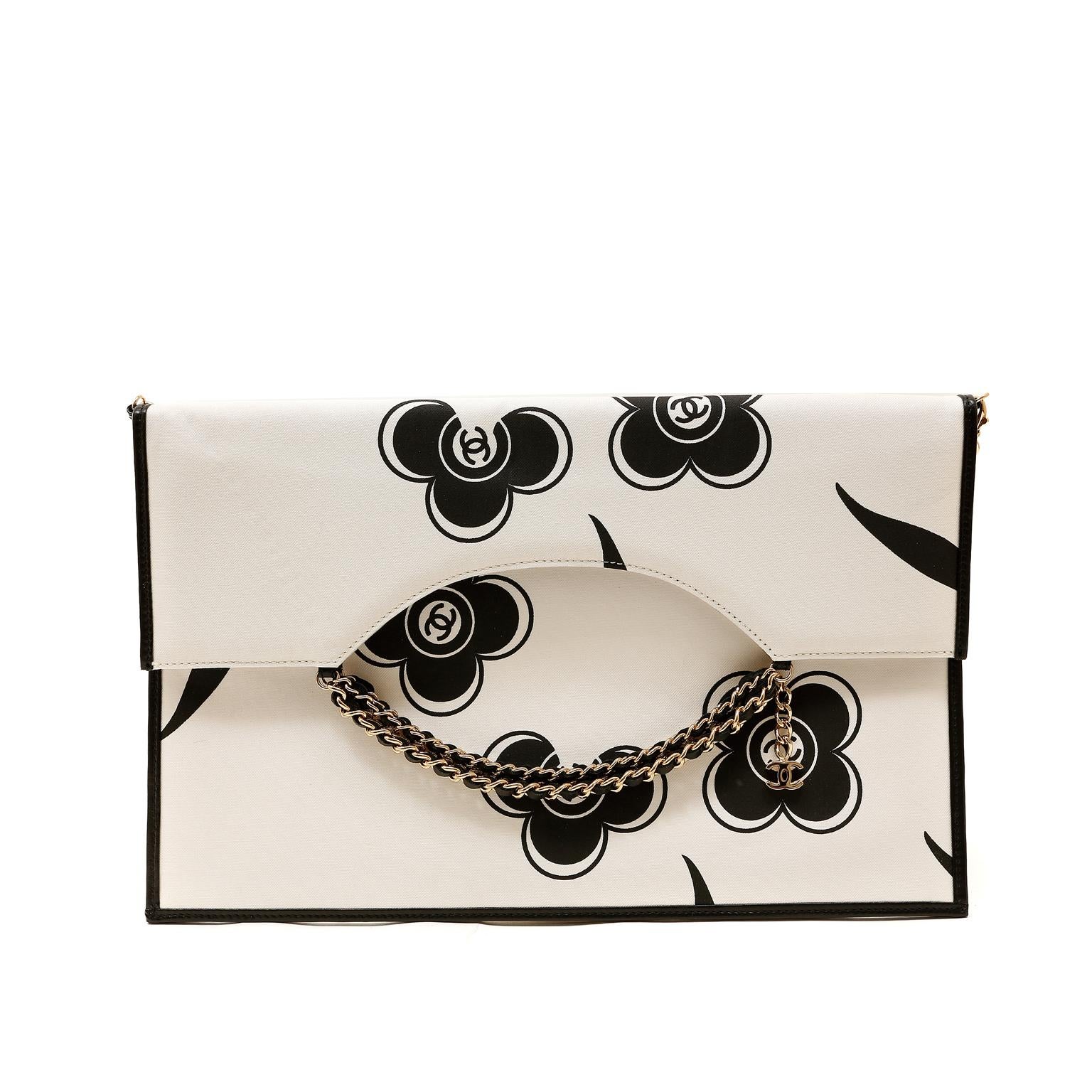 This authentic Chanel Ivory and Black Camellia Envelope Clutch is in pristine condition.  The contrasting neutrals and chain details make this versatile bag a brilliant complement to any ensemble.  
Ivory fabric slim envelope clutch has black