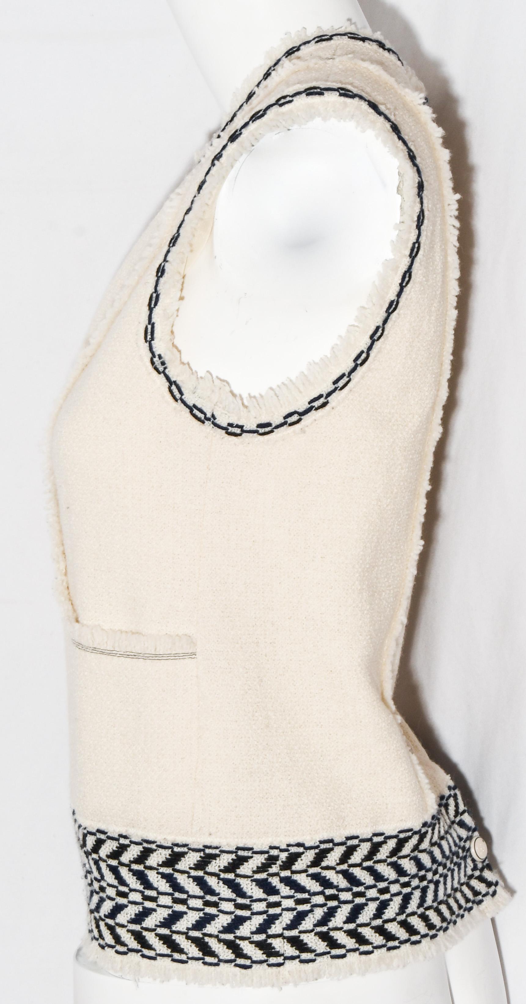 Chanel woven ivory wool sleeveless top features contrasting chain link stitch detailing in black and navy around round neckline and armholes.   With frayed fringe trim, around neckline and armholes but, also, including this trim on the hem and the