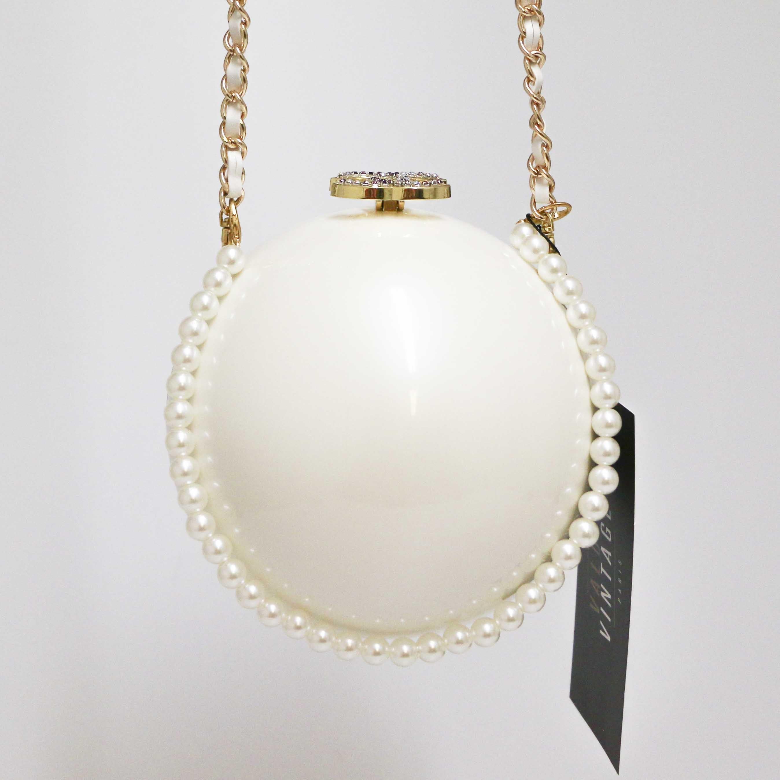 CHANEL ivory color sphere bag with pearl strap. It is made with plexiglass, CC set with rhinestones, handle chain in gilt metal. Toggle clasp. Removable double shoulder straps. The lining is in black velvet.
Worn crossbody or carried in the hand by