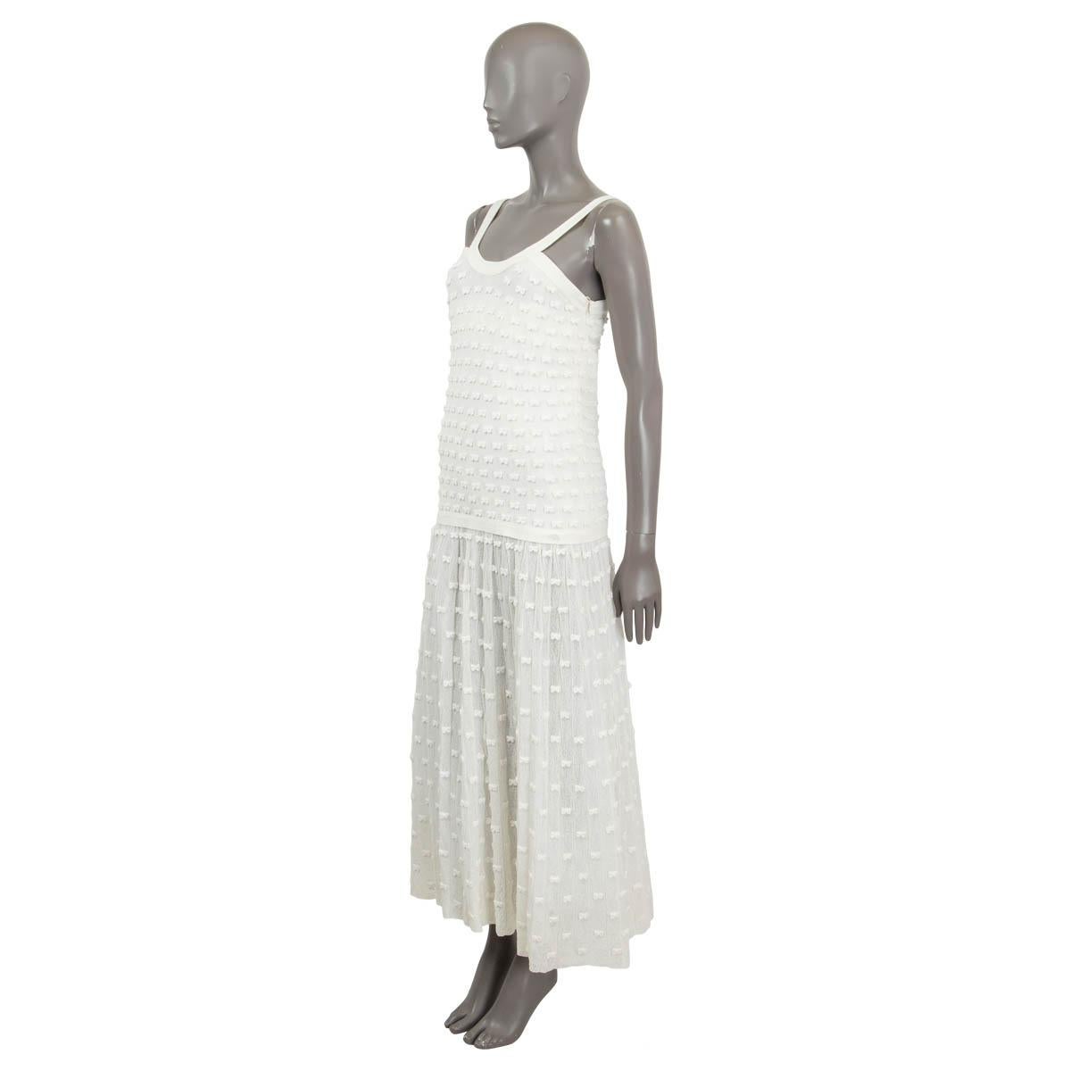 100% authentic Chanel maxi dress in ivory cotton (51%), polyamide (46%) and elastane (3%) with a thin fond over the skirt in ivory polyamide (100%). Features an embellishment of small bows all over, a round neck and a flowy flared skirt. Opens with
