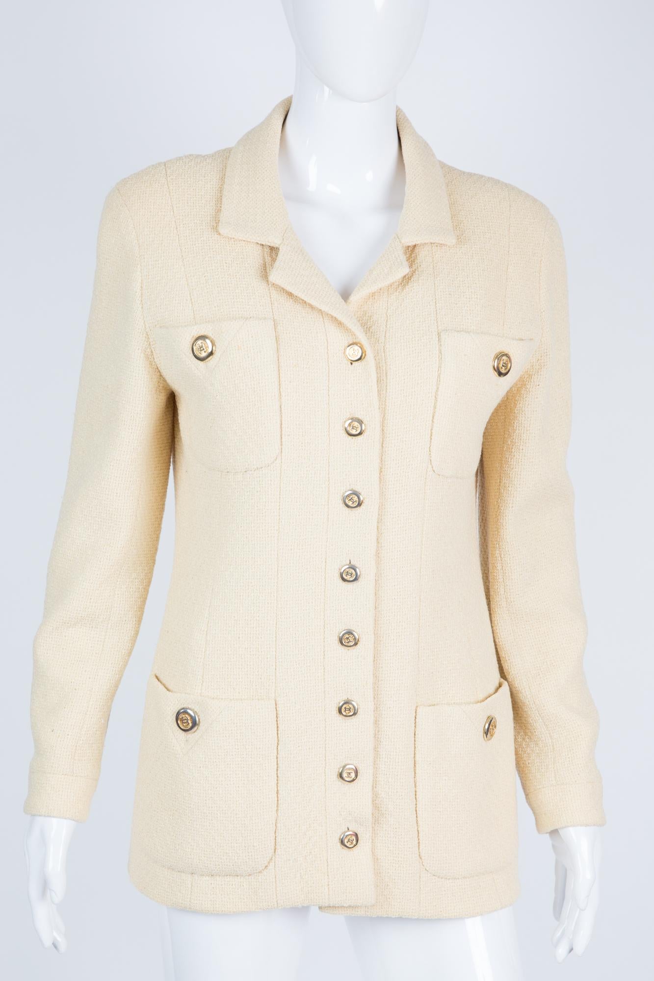 Chanel long ivory wool boucle Chanel jacket featuring a long length,  front logo buttons, long sleeves with logo buttons, a back slit with logo buttons, a silk logo lining , and a 24kt gilded gold hardware chain in the bottom lining.
Composition: