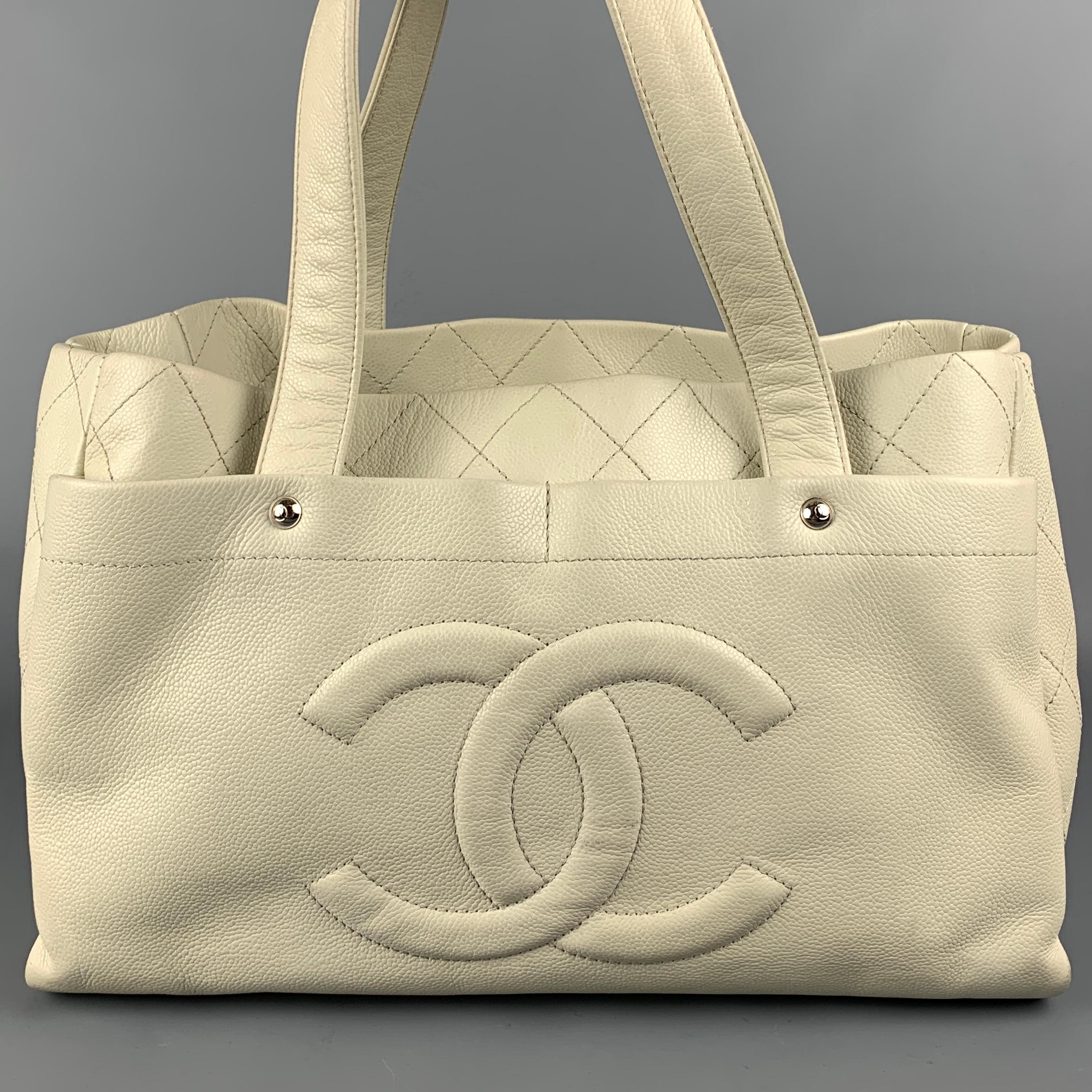 CHANEL handbag comes in a ivory quilted leather featuring double top handles, front & back double pockets, inner slots, silver tone hardware, front logo detail, and a snap button closure. Includes dust bag and cosmetic case. Made in France.

Very